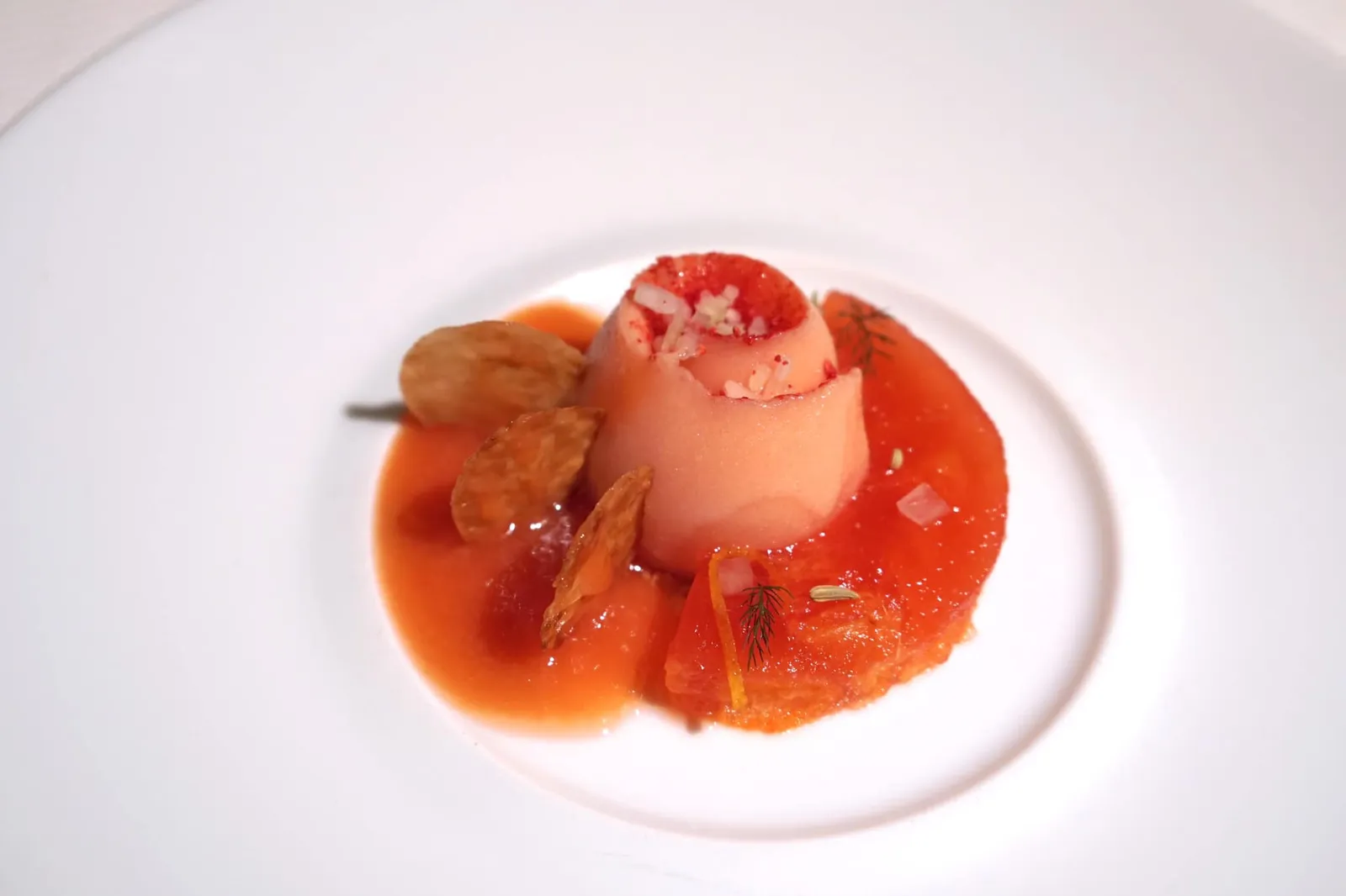 Textures of blood orange and fennel Consistances d'orange sanguine et fenouil Blood orange jelly with blood orange ice, perfumed with fennel; croustillant biscuit with orange zest. ขนมหวานอย่างแรกคือส้ม “บลัดออร์เร้นจ์” เสิร์ฟมาในหลากหลายเนื้อสัมผัส เริ่มจากชิ้นบลัดออร์เร้นจ์ทางขวา และเจลลี่บลัดออร์เร้นจ์ทางซ้าย ยังมีบลัดออร์เร้นจ์ไอซ์ที่มีกงฟีเฟนเนลอยู่ตรงกลาง มีกลิ่นหอมของเฟนเนล แผ่นกรอบ Croustillant biscuit สามชิ้นรอบ ๆ ทำมาจากผิวของบลัดออร์เร้นจ์ ก่อนทานพนักงานจะราด Juice หรือน้ำบลัดออร์เร้นจ์ลงไป ความสุดยอดของจานนี้คือเนื้อสัมผัสของส้มบลัดออร์เร้นจ์ที่ทำออกมาเป็นเจลลี่นุ่ม ๆ จนเกือบละลายในปาก ทั้งยังมีเนื้อสัมผัสอันหลากหลาย มีรสขมนิด ๆ พอเป็น Aftertaste ผสานเข้ากับกลิ่นหอมของเฟนเนลได้อย่างไร้ที่ติ (20/20)