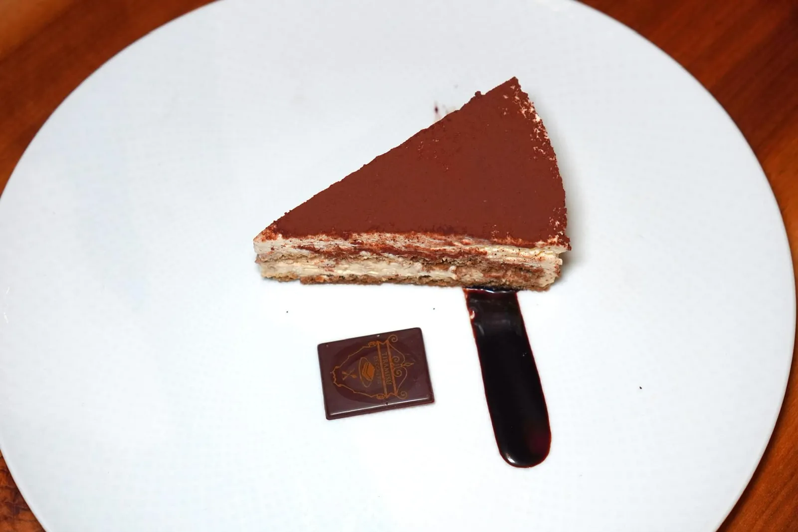 Beccherie Treviso Tiramisú (9 €) ขั้นตอนการเตรียมอาหารหวานที่เต็มไปด้วยความเรียบง่ายจานนี้เริ่มต้นด้วยการผสมไข่แดงเข้ากันกับน้ำตาล จากนั้นเติม Mascarpone ลงไปผสมรวมกันจนได้เป็น Soft Cream จากนั้นนำบิสกิต Lady Finger จุ่มลงในกาแฟจนชุ่มกำลังดีและอ่อนตัวลง ทั้งยังให้รสชาติขมนิด ๆ ที่พอเหมาะ เมื่อจับคู่กับความหอม มัน และครีมมี่ของ Soft Cream พบว่าเข้ากันได้อย่างลงตัวไร้ที่ติ ในปัจจุบันเชฟเลือกที่จะโรยผงโกโก้ให้ทั่วพื้นผิวด้านบนแทนที่การโรยเป็นรูปสัญลักษณ์ของร้านแบบดั้งเดิมและย้ายรูปสัญลักษณ์มาไว้ในช็อกโกแลตทรงสี่เหลี่ยมเพื่อเสิร์ฟมาข้าง ๆ กันนั่นเอง (15/20)