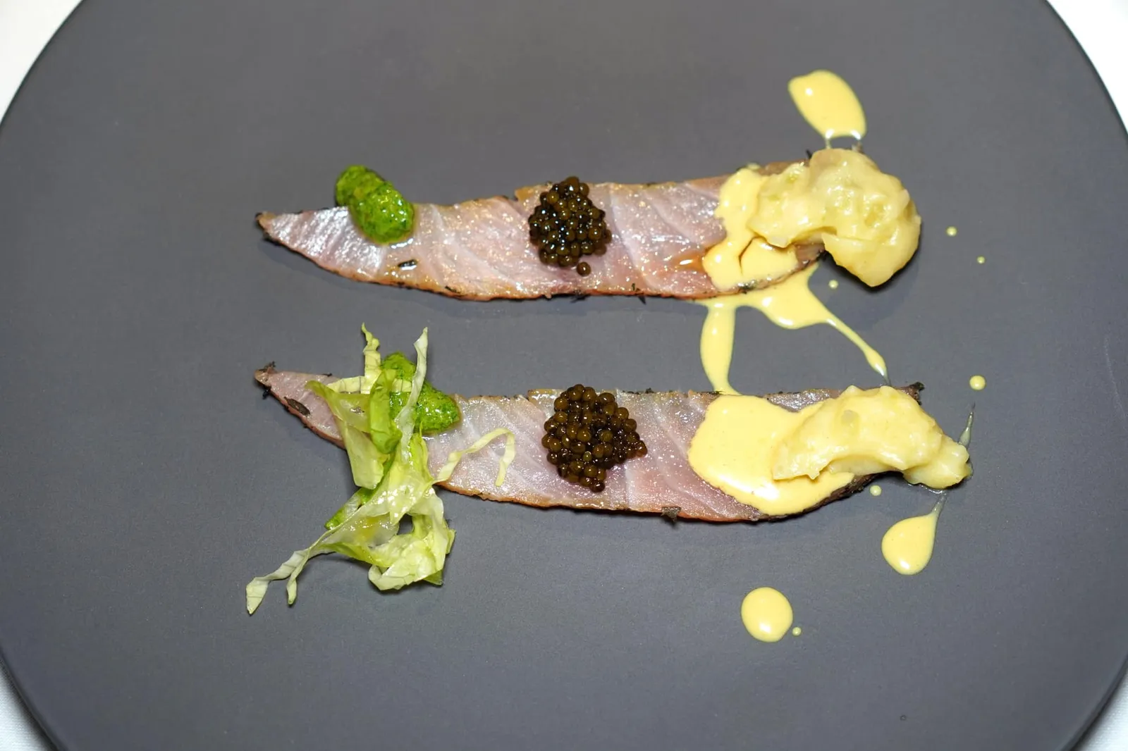 AMBERJACK WITH WATER PEPPER Smoked eel brandade, parsley and amberjack juice ปลา Amberjack เสิร์ฟมาแบบดิบเพื่อให้ได้เนื้อสัมผัสที่ดีโดยธรรมชาติของเนื้อปลา ด้านบนท็อปด้วย Kaluga Amur Caviar ฝั่งซ้ายมือคือองค์ประกอบของพาสลีย์ และฝั่งซ้ายมือคือองค์ประกอบของมันฝรั่ง จากนั้นราดด้วยครีมที่เตรียมมาจากส่วนท้องของปลา Amberjack ลงไปอีกทีหนึ่ง (15/20)