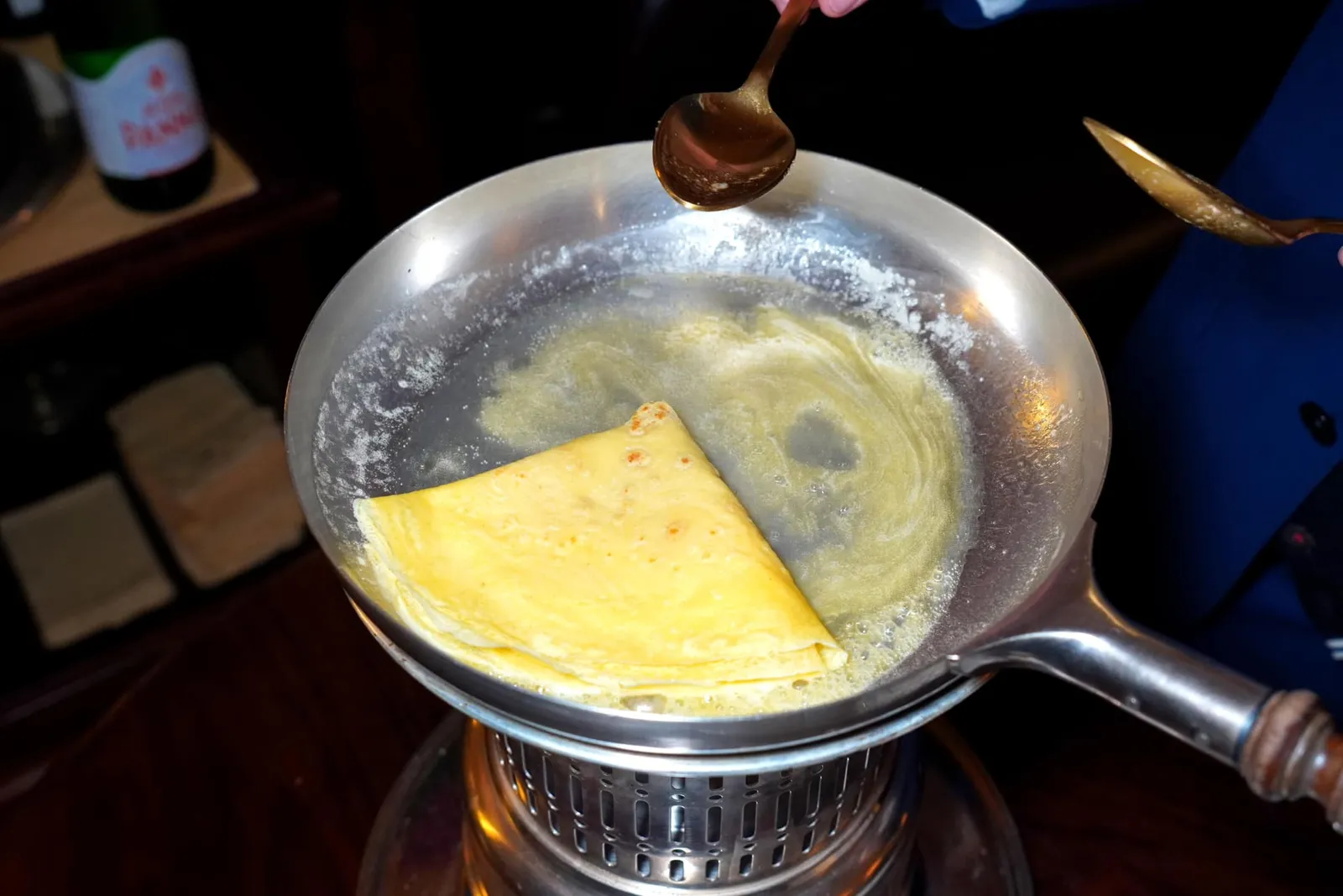 La nostra Crêpe Suzette alla lampada con gelato alla crema e scorza di limone พนักงานจะละลายเนยและน้ำตาลในกระทะร้อน ๆ จากนั้นจึงเติมน้ำส้มและเหล้าลงไปก่อนจะนำแป้งเครปลงไปคลุกให้ทั่วกัน (17/20)