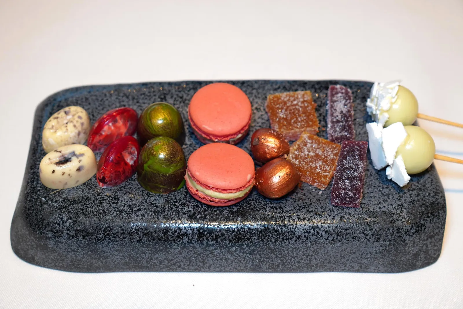 Petits fours ในถาดประกอบไปด้วย Basil Lolipop, Passionfruit Jelly, Strawberry Gummy, Lemon Chocolate with Jelly, Red Fruit Macaron, Hazelnut Praline, Mango and Curry Bonbon