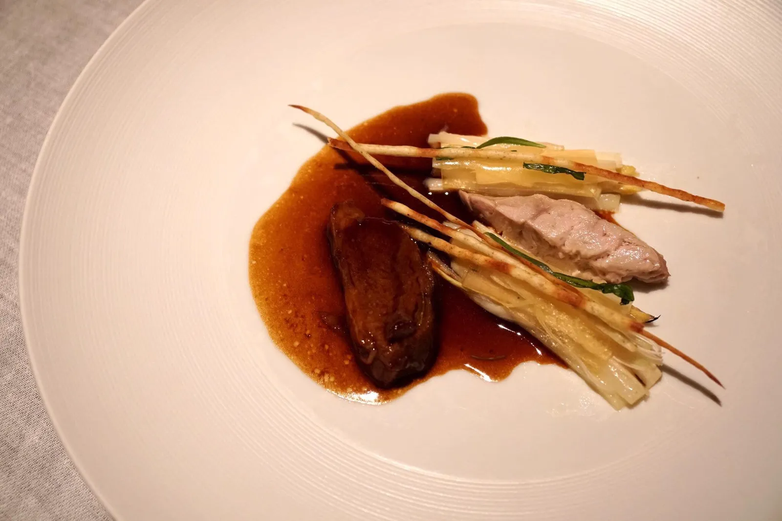 MILK–FED VEAL Veal Cheeks & Brain with white Asparagus, Spruce Tips & ‘Topaz’ Apple ด้านซ้ายคือส่วนแก้มวัวเคี่ยวกับสปรูซ (Spruce) และสตูว์แก้มลูกวัว อีกฝั่งคือ *** สมองลูกวัว *** นำไปต้มด้วยไฟคงที่จนมีเนื้อสัมผัสนุ่ม เนียน สมองที่ทางร้านทำออกมาถือว่ากลิ่นเบามาก ตรงกลางคือหน่อไม้ฝรั่งขาวส่วนหนึ่งนำไปย่างและบางส่วนนำไปต้ม ด้านบนเป็นเเท่งบางๆคือยอดสปรูซทอดกรอบ รองด้านล่างด้วยเจลลี่ทำจากโทปาซแอปเปิ้ล มะนาว และไซรัปทำจากยอดสปรูซ และยังมีส่วนประกอบของทารากอน