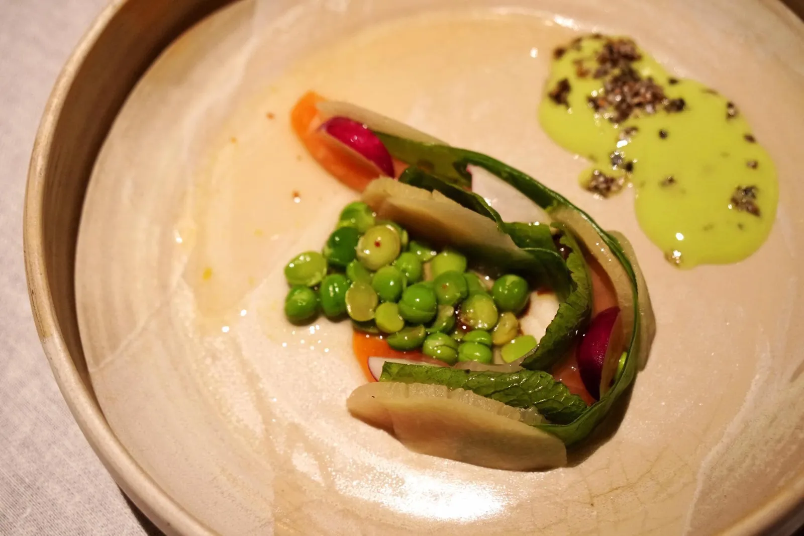 SALMON TROUT Salmon Trout with young Peas, Kohlrabi & Scottish Lovage จานนี้คือปลาแซลมอนเทร้าท์สดๆจาก Ramsau เมืองในเเคว้นบาวาเรียประเทศเยอรมัน และเป็นที่ตั้งของอุทยานแห่งชาติ Berchtesgaden ด้วยความที่เป็นแซลมอนป่าทำให้มีมีเนื้อเนียน นุ่ม ละมุนลิ้น ไม่มีกลิ่นคาว ทานกับผักเคียงต่างๆคือ โคลราบีสดที่นำไปอบในเตาอบ โคลราบีดองกับเอลเดอร์ฟลาวเวอร์และเวอจูส ใส่เมล็ดถั่วลันเตาตรงกลาง ส่วนตัวซอสเป็นซอส Mountain trout garum หรือน้ำปลาหมักภายใต้อุณหภูมิคงที่ค่าหนึ่ง สูตรนี้ใช้กันมาตั้งเเต่ยุคกรีกและโรมัน ได้จากการนำปลาไปหมักกับเกลือจนได้น้ำจากตัวปลามาส่วนหนึ่ง ต่อมานำไปกรองกากออกออกแล้วหมักต่อจนได้เป็นการุม นอกจากนี้ยังมีซอสสีเขียวข้างๆทำจากถั่วลันเตาโรยด้านบนด้วยหนังปลาเทร้ากรอบ