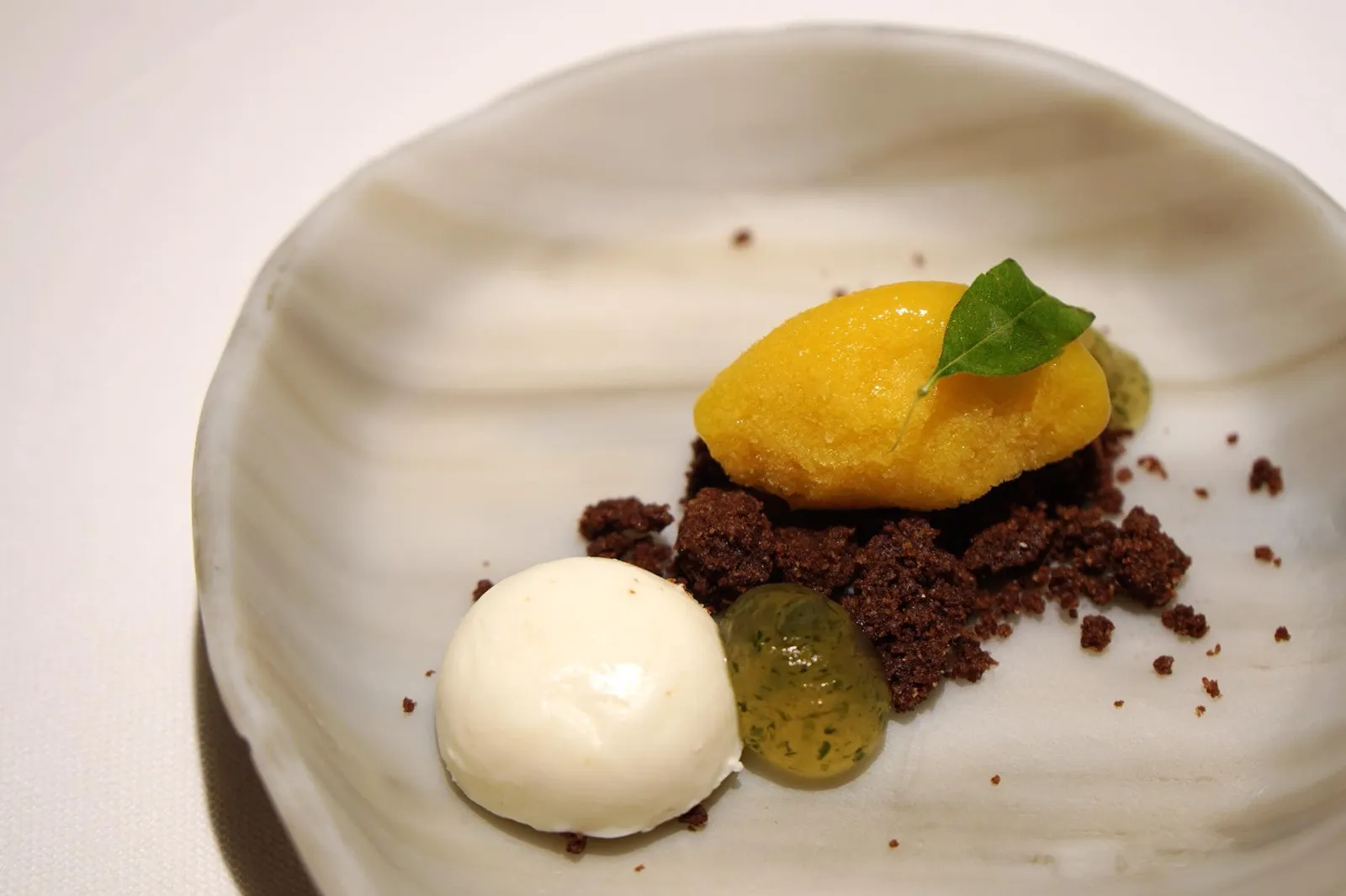 Pre-dessert (Complimentary) Passion fruit ice cream สำหรับพรีเดสเสิร์ททางร้านนำเสิร์ฟเป็นไอศกรีมเสาวรสรสเปรี้ยว เสิร์ฟให้ก่อนของหวานเพื่อดับคาว สีขาวคล้ายมูสคือรีคอตต้าผสมวานิลลาหอม หวาน อร่อย มีครัมเบิ้ลทำจากผงโกโก้ เจลลี่เขียวทำจากมะนาว รสชาติค่อนข้างขม ปกติเเล้วเสารสกับโกโก้ไม่น่าจะเข้ากันได้เเต่การที่เขฟเลือกใช้วานิลลาเเละรีคอตต้ามาเป็นตัวเชื่อมรสชาติทำให้ทั้งสองอย่างทานพร้อมกันได้อย่างลงตัว ถือว่าทำออกมาได้ดี อร่อยมากจริงๆ (15/20)
