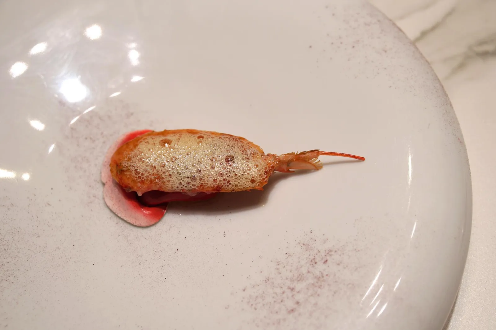 LANGOUSTINE'S HEAD WITH "SAUCE" OF BITTER SWEET LEMONS. ส่วนหัวของกุ้งเเลงกูสทีนทานกับโฟมทำจากมะนาว ด้านบนคือ Cow butter ผงสีชมพูคือ Dust of Hibiscus หรือดอกชบา วิธีทานให้ใช้นิ้วลูบฝุ่นชบาทานก่อนจากนั้นค่อยทานหัวกุ้งตาม เพราะรสเปรี้ยวของชบาจะทำให้รสหวานมันหัวกุ้งเด่นชัดมากยิ่งขึ้น ส่วนด้านล่างรองด้วยยางรูปลิ้นดูแปลกตา (19/20)