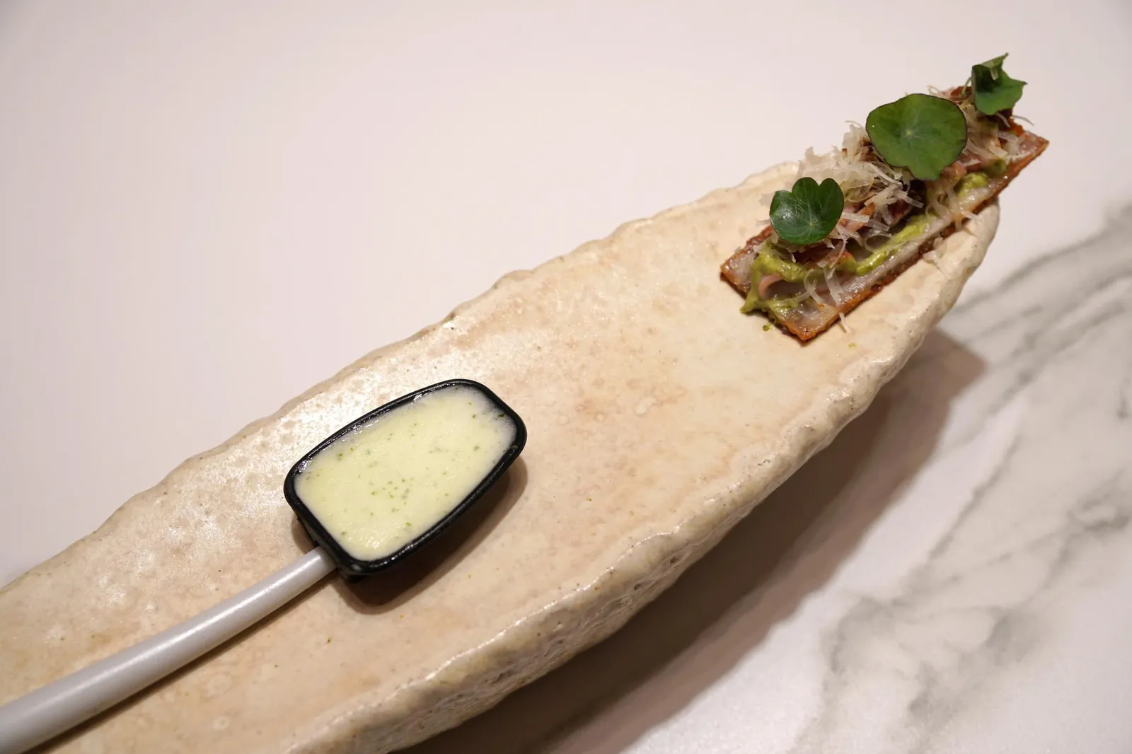 CRUNCHY "CANAPÉ" OF SUCKLING PIG SKIN, LITTLE SQUIDS, MATURE TOMATOES & DRIED LITTLE SQUIDS MARMALADE, CHARGRILLED "HABANERO" CHILLIES PURÉE & IDIAZABAL CHEESE, FROZEN GREEN LEMON WITH CORIANDER ROOT. คั่นกลางด้วยอาหารว่างอย่าง Cochinillo หรือหมูหันหนังกรอบ กรอบชนิดเคี้ยวเเล้วมีเสียงดังกร๊อบออกมาจากในปาก มีกลิ่นหอม ด้านบนมี Chopitos หรือหมึกตัวเล็กจากตอนเหนือของประเทศสเปนซอยเป็นชิ้นๆมีเนื้อสัมผัสเคี้ยวหนึบตัดกันกับความกรอบของหมูหัน มีมะเขือเทศช่วยเพิ่มรสเปรี้ยวอูมามิ เเละยังมีมีเเยมที่ทำจากหมึกเช่นกัน ด้านบนคือพูเรทำจากพริกหวานฮาบาเนโร่ มีองค์ประกอบของไอดีอาซาบัล ชีสนมแกะจากทางตอนเหนือของสเปน ส่วนสีเขียวในช้อนข้างกันคือไอศกรีมทำจากมะนาวผสมกับรากผักชีช่วยเพิ่มรสเปรี้ยวเเละกลิ่นเฉพาะตัวให้กับจาน (19/20)