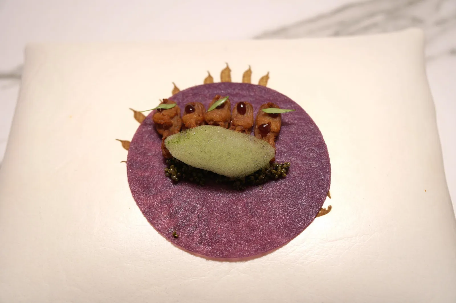 “TACO-CREPE” OF PURPLE CORN WITH CRUNCHY DUCK TONGUES, CUCUMBER & TONBURI. จานถัดมายังคงอยู่ที่ประเทศจีน คอนเซปของจานนี้คือ “เป็ดปักกิ่ง” สไตล์ Diver XO เริ่มจากตัวแป้งที่ทำจากข้าวโพดม่วง มีเนื้อสัมผัสนุ่มละมุนตามแบบฉบับแป้งเครปที่ดี เชฟเปลี่ยนจากการใช้หนังเป็ดแบบต้นตำรับมาใช้ “ลิ้นเป็ด” ทอดมาแบบๆกรอบเสิร์ฟแทน ด้านบนคือซอส Hoisin รสหวานหอม ข้างๆกันคือโฟมแตงกวาดอง อีกหนึ่งทีเด็ดด้านล่างคือ Tonburi วัตถุดิบที่ได้รับสมญานามว่า Land caviar เป็นเมล็ดของต้น Cypress มีเนื้อสัมผัสเคี้ยวหนึบคล้ายไข่ปลาคาเวียร์จริงๆ ทุกองค์ประกอบเข้ากันได้อย่างดี ทานเเล้วชวนนึกถึงเป็ดปักกิ่งชั้นดีตามห้องอาหารติดดาวในฮ่องกง แต่ถูกนำมาพัฒนาต่อยอดไปอีกหลายขั้น สุดยอดมากๆ (20+/20)