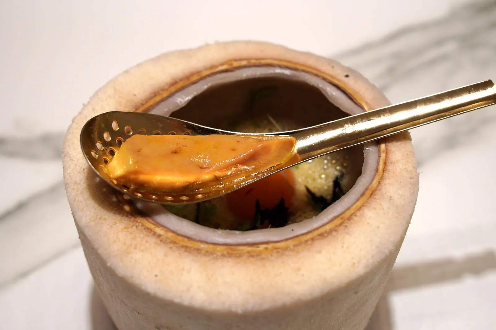 STEAMED FOIE RAMEN, GUINEA FOWL'S BONES SOUP EMULSIFIED WITH ITS FOIE AND ROASTED YOLK. จานถัดมาคือราเมงเสิร์ฟมาในลูกมะพร้าว น้ำซุปทำมาจากกระดูกของไก่ต๊อก ภายในมีเส้นราเมง เห็ดต่างๆรวมถึงทรัฟเฟิล เเละ Hen egg yolk ด้านบนคือฟัวส์หรือตับเป็ดที่ผ่านการเเช่ในกระเทียมต้น 1 วัน เเละเเช่ในเกลืออีก 1 ชั่วโมง จากนั้นผ่านความร้อนเป็นระยะเวลาสั้นๆเพียง 3 วินาที (17/20)