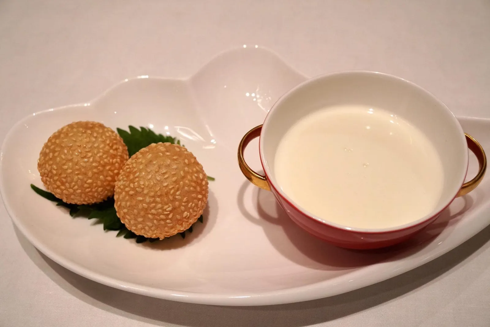 煎堆生磨蛋白杏仁露 (14 €) Crème d’amande en coque de sésame croustillante (20 minutes de préparation) Sweetened egg-white almond cream with crispy sesame ball (20 minutes preparation) อัลมอนต์ครีมไข่ขาว อีกหนึ่งเมนูอาหารหวานคลาสสิค สำหรับสูตรของ Shang Palace สาขากรุงปารีสถูกปรับให้ชาวต่างชาติทานได้ง่ายขึ้น กลิ่นของไข่ขาวไม่เเรงมากเหมือนสูตรฮ่องกงต้นตำรับ ตัวซุปมีความนุ่มเนียนมากกว่าปกติ หอมกลิ่นอัลมอนต์คล้ายกับขนมของฝรั่งเศสมากกว่าจะเป็นขนมของจีน เสิร์ฟมาให้ทานคู่กับงาทอดกรอบไม่มีไส้ ถือว่าทางปรับสูตรออกมาได้น่าสนใจ (17/20)