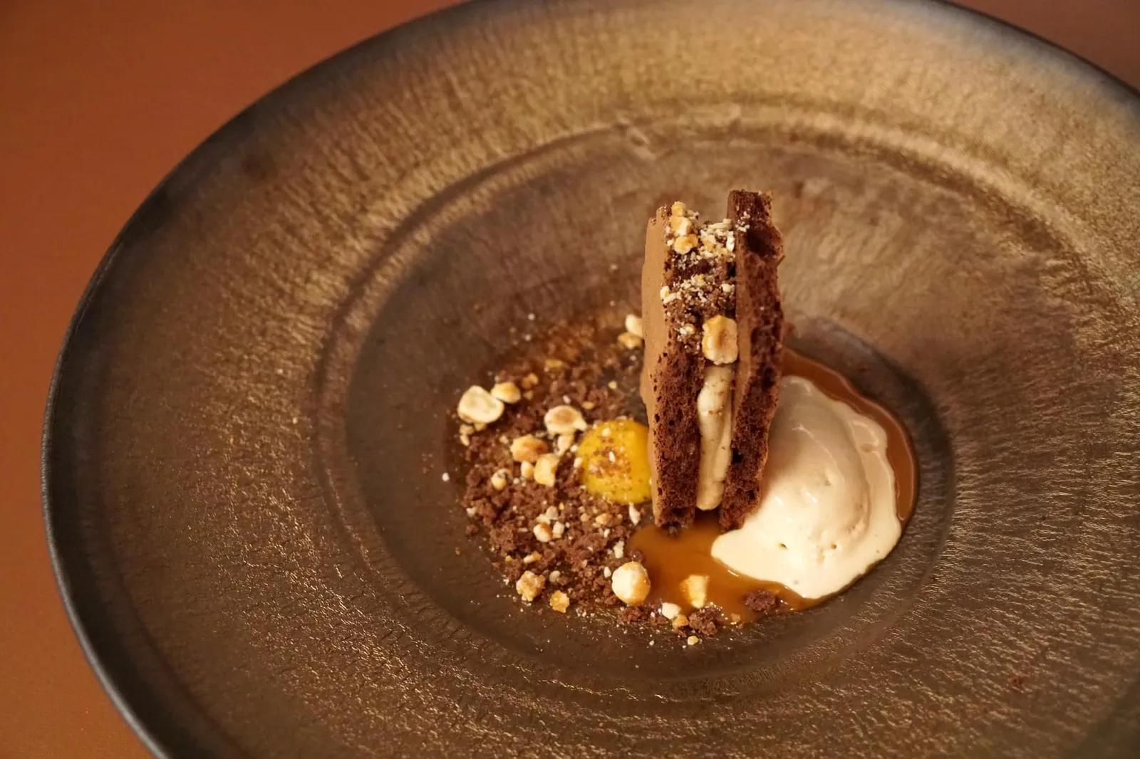 Chocolate cake, anise sabayon, caramel, praline ice cream สำหรับของหวานอย่างแรกคือช็อกโกแลตเค้กชิ้นโตที่วางตั้งสูงขึ้นมาจากจาน ฝั่งซ้ายคือครัมเบิ้ลกรอบ ซาบายองโป๊ยกั๊ก ฝั่งขวาคือซอสคาราเมลเละไอศกรีมพราลีนรสหวาน (15/20)