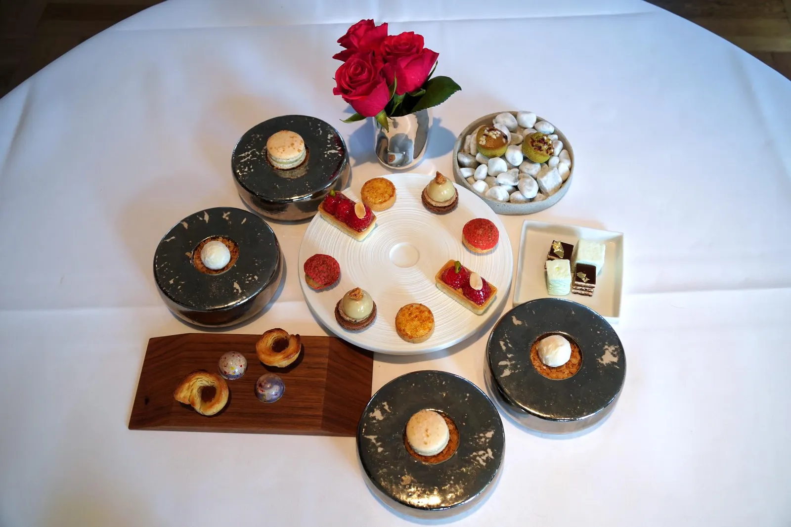 Nos Petites Sucreries Macaron of Vanilla / Praline of White Chocolate Filled with Passion Fruit / French Bread with Salted Caramel / Praline with Cassis / Crème Brûlée of Tonka Bean / Tartelette of Banana / Tartelette of Raspberry and Hazelnut / Raspberry Tartlette / Financier with Matcha Tea / Opera Cake with Coffee / Marshmallow with Green Apple หากใครที่ยังรู้สึกไม่อิ่มดีทางร้านพร้อมปิดท้ายมื้ออาหารของคุณด้วยขนมหวานขนาดจิ๋วเซ็ตใหญ่ถึง 11 อย่าง !!! เรียงตามลำดับดังนี้ เริ่มจากมาการองวานิลลาและพราลีนไวท์ช็อกโกแลตสอดไส้เสาวรสรสเปรี้ยว ทั้งคู่เสิร์ฟมาบนจานสีเงิน ถัดมาคือขนมปังแบบฝรั่งเศสทานกับคาราเมลรสหวานเค็มเละพราลีนสอดไส้ไวน์คาสซิสเสิร์ฟมาบนจานไม้ทรงสี่เหลี่ยม จานสีขาวทรงกลมตรงกลางประกอบไปด้วยขนมเครมบรูเล่ทรงกลมทำมาจากถั่วปากอ้า ชิ้นนี้อร่อยเลิศจนน้ำตาแทบไหล เนื้อเครมบรูเลนุ่ม ละมุน ละลายในปาก มีกลิ่นหอมของถั่วปากอ้าพร้อมกับรสขมนิดๆจากเลเยอร์เเข็งบางๆที่ถูกทอร์ชมาด้านบนเป็นอาฟเตอร์เทส ฟินมากจริงๆ ถัดมาคือทาร์ตเล็ตขนาดจิ๋วที่มีกลิ่นหอมของกล้วยเด้นชัดเจน ต่อด้วยทาร์ตสีแดงที่หน้าดูเหมือนขนม Choux มากกว่ามีส่วนผสมของราสเบอร์รี่เเละถั่วฮาเซลนัท เเละชิ้นสุดท้ายบนจานนี้คือมินิทาร์ตทรงสี่เหลี่ยมที่มีผลราวเบอร์รี่ชิ้นโคอยู่ตรงกลาง ฟินองซิเยมัทฉะเนื้อเเน่น หอมกลิ่นชาเขียวเบาๆเสิร์ฟมาบนก้อนหินในจานมุมขวาบน ปิดท้ายด้วยคลาสสิคเค้กโอเปร่าที่มีส่วนผสมของกาแฟ และมาร์ชเเมลโล่นุ่มนิ่มที่มีกลิ่นหอมของแอปเปิ้ลเขียว ขนมทั้ง 11 อย่างทำออกได้ดีไร้ที่ติสมกับมาตรฐานห้องอาหารฝรั่งเศส 3 ดาวมิชลิน เชื่อเลยว่ามีหลายคนที่อาจทานไม่หมด เเต่ไม่ใช่กับเราผู้ที่ชื่นชอบของหวานเป็นการส่วนตัว นี่ก็นั่งทานเรื่อยๆจนหมดเลยล่ะ 😂 (19/20)