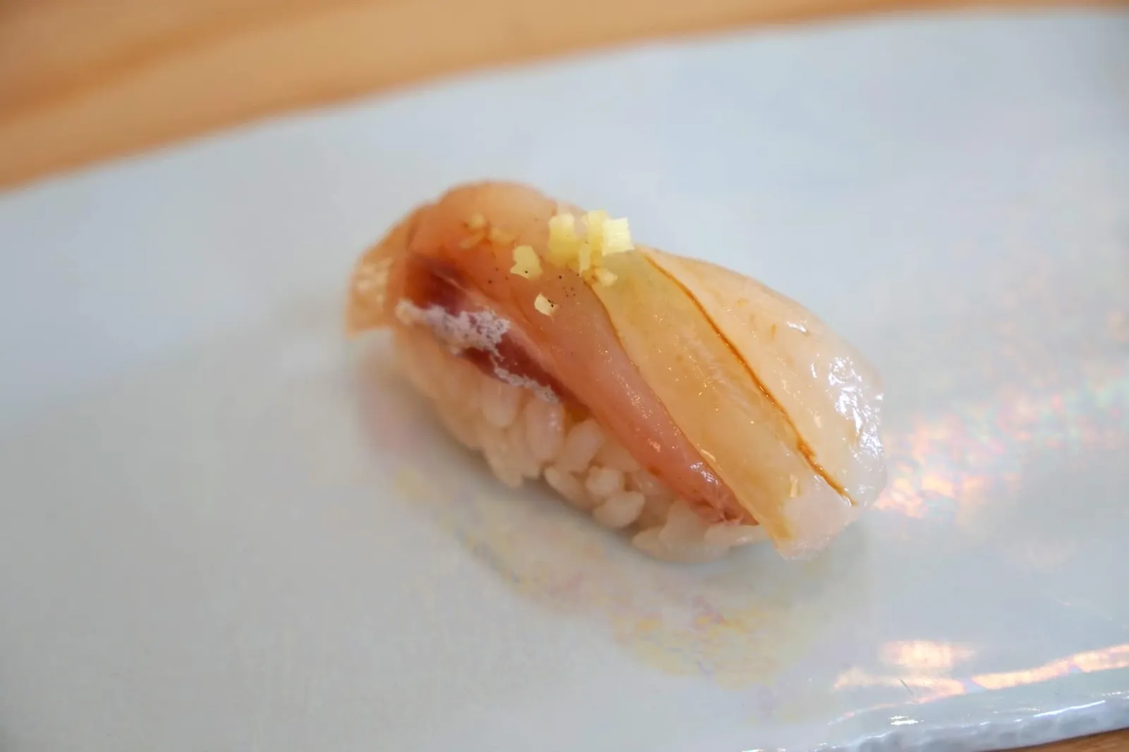 鱸 Ike-jime sea bass ต่อด้วย "Susuki" หรือปลากระพงที่ถูกเตรียมด้วยเทคนิคอิเคะจิเมะ (活け締め) แบบญี่ปุ่นดั้งเดิมดังที่ได้กล่าวไปข้างต้นทำให้นิงิริปลากระพงคำนี้มีเนื้อสัมผัสที่นุ่ม ละมุนลิ้นมากกว่าปกติจากการที่เนื้อปลาไม่หดรัดตัวขณะตาย ทั้งยังมีรสหวานแบบธรรมชาติ ตัดด้วยรสของขิงสดที่ทอปมาอยู่ด้านบน โดยปกติเเล้วนิงิริซูชิของปลาในกลุ่มปลากระพงมักเป็นคำที่ถูกยกมามาคั่นกลาง และมีรสชาติไม่โดดเด่นมากนัก แต่สำหรับคำนี้ขอยกคะเเนน 18/20 ให้กับเทคนิคเเละรสชาติที่เชฟทำออกมา สุดยอดจริงๆ (18/20)