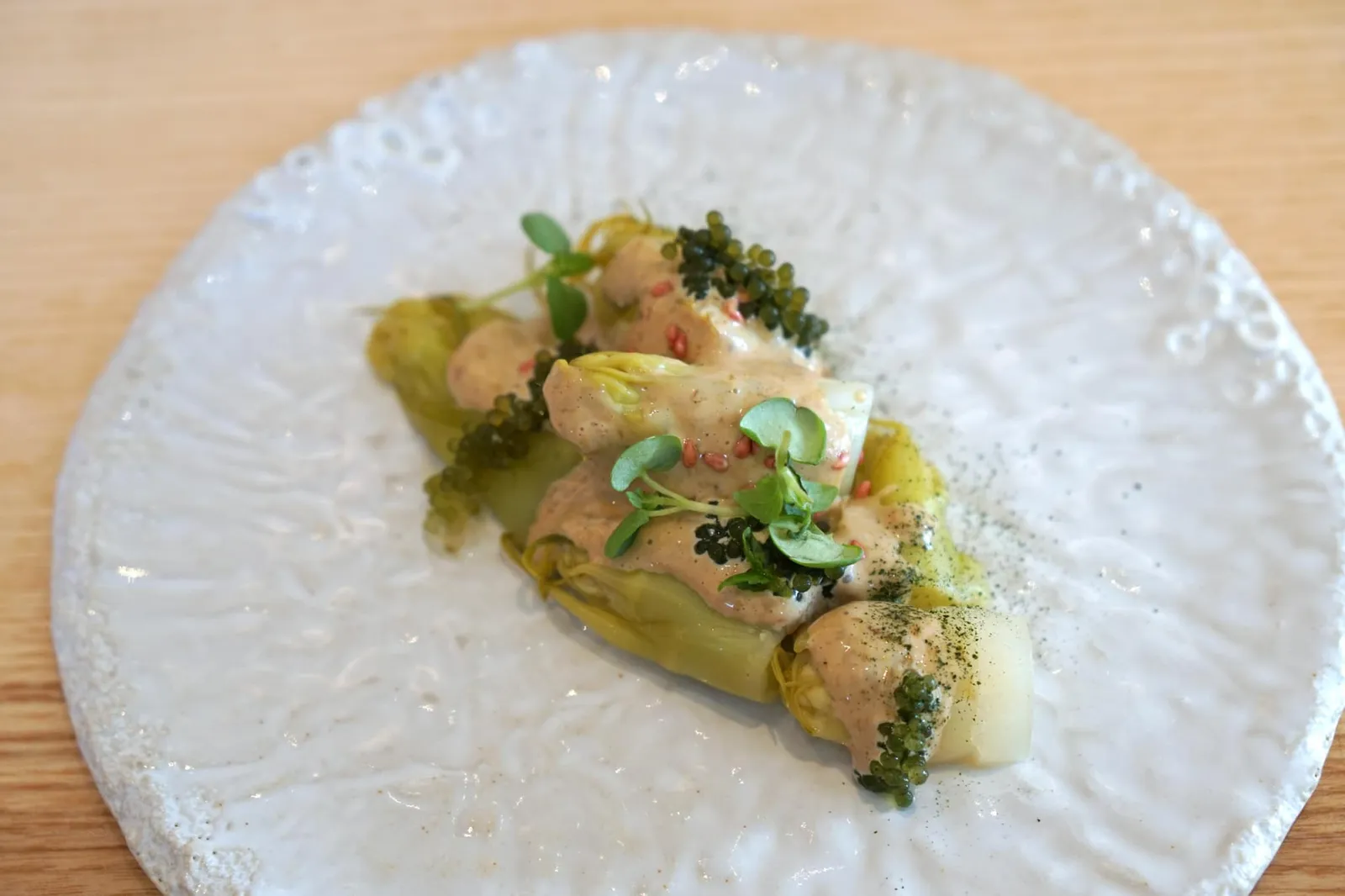 プンタレルのサラダ 刺身 Puntarelle tsukemono, seaweed jam sauce ปิดท้ายอาหารเรียกน้ำย่อยด้วยผัก Puntarelle จากประเทศอิตาลี มีเนื้อสัมผัสเคี้ยวกรอบเป็นเอกลักษณ์ ทานกับสึเกะโมโนะหรือผักดองแบบญี่ปุ่นโดยในที่นี่เชฟเลือกใช้เป็นกะหล่ำปลีดองมีรสเปรี้ยวนำช่วยเรียกน้ำย่อยได้ดีมากๆ เสิร์ฟให้ทานกับซอสทำจากสาหร่าย ผงสาหร่าย ทอปด้านบนด้วย Sea grape ซึ่งเป็นสาหร่ายทะเลชนิดหนึ่งเช่นกันช่วยเพิ่มรสอุมามิก่อนเข้าคอร์สนิงิริซูชิ (18/20)