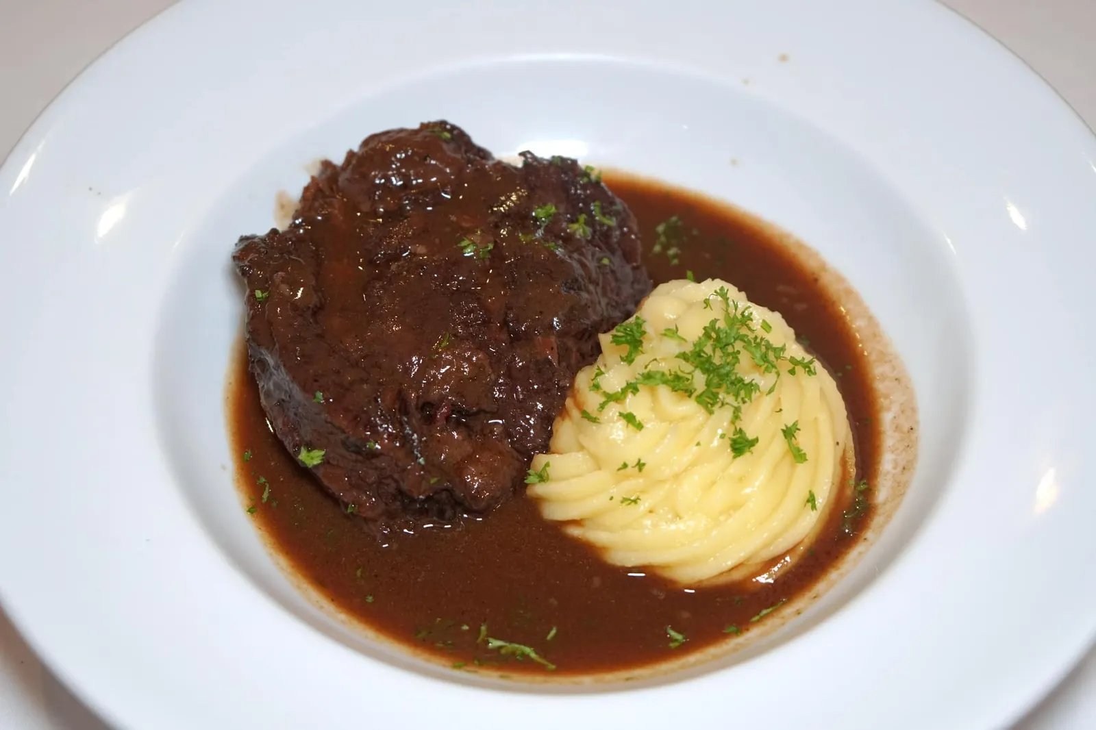 Beef Cheek Bourguignon (790++) Beef cheek stew braised in red wine and brown stock served with mashed potato มาถึงอาหารจานหลักเราขอแนะนำให้สั่ง “บูร์กอญ” หรือสตูว์เนื้อวัวตุ๋นไวน์แดงที่มีต้นกำเนิดมาจากแคว้นเบอร์กันดี เชฟเริ่มจากการคัดเนื้อส่วนส่วนแก้มวัวมาแต่งขอบ จากนั้นหมักข้ามคืนด้วยไวน์แดง ก่อนที่วันรุ่งขึ้นจะนำไปจี่บนกระทะจนขึ้นสี นำไปตุ๋นต่อในไวน์แดงเดิมแล้วใส่หอมแดง แครอท หอมใหญ่ เบลีฟลงไปอีกอย่างน้อย 6 เพื่อให้เนื้อมีความฉ่ำนุ่มและดูดน้ำซอสเข้าไปแทรกในใยกล้ามเนื้อ จัดว่าเป็นจานที่ใช้เวลาในการเตรียมสูงมากที่สุดจานหนึ่งในร้านเลยก็ว่าได้