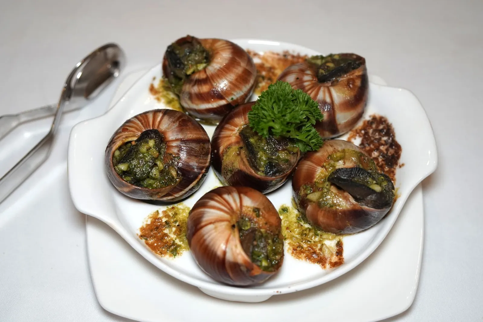 Escargot (6pcs) (490++) Baked French escargot in shell with Café de Paris sauce เริ่มต้นมื้ออาหารด้วยเมนูคลาสสิคอย่างเอสคาโกท์หรือ “หอยทาก” นำเข้ามาจากประเทศฝรั่งเศสโดยตรง เชฟนำไปอบทั้งเปลือกกับซอสเนย-กระเทียมสุดคลาสสิคอย่าง Café de Paris แม้จะมีคำว่าปารีสอยู่ในชื่อแต่ตัวซอสกลับมีต้นกำเนิดมาจากร้านคาเฟ่ชื่อเดียวกันในรุงเจนีวาช่วงปี 1930 ก่อนที่จะได้รับความนิยมแพร่หลายไปทั่วโลกในเวลาต่อมา ที่ร้าน Aubergine เชฟปรับสูตรโดยการเพิ่มแองโชวี่ลงไปเล็กน้อยเพื่อให้กลิ่นหอมมากยิ่งขึ้น