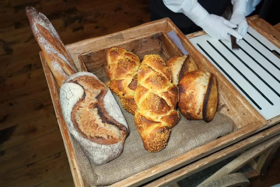 Bread and Butter จากนั้นพนักงานจะนำเสิร์ฟขนมปังเพิ่มเติมอีก 4 ชนิด เริ่มจาก Authentic Sourdough ผิวกรอบ เนื้อด้านในรสชาติอมเปรี้ยวนิด ๆ นุ่มหนึบกำลังดี ถัดมาคือ Corn Bread ทำมาจากแป้งข้าวโพด ด้านในมีเมล็ดข้าวโพดปนอยู่ท็อปด้านบนด้วย Corn Crumble ช่วยให้ความกรอบมีมิติที่หลากหลาย ฝั่งขวาสุดคือ Potato Bread ด้านในมี Mashed Potato และ Fresh Potato ให้ลักษณะเป็นมันฝรั่งบด สุดท้ายชิ้นด้านหลังเป็น Traditional French Baguette ขนมปังทุกชนิดเตรียมออกมาได้อย่างไร้ที่ติเช่นเคยจนสร้างความประทับใจให้กับเราได้อย่างไม่น่าเชื่อ