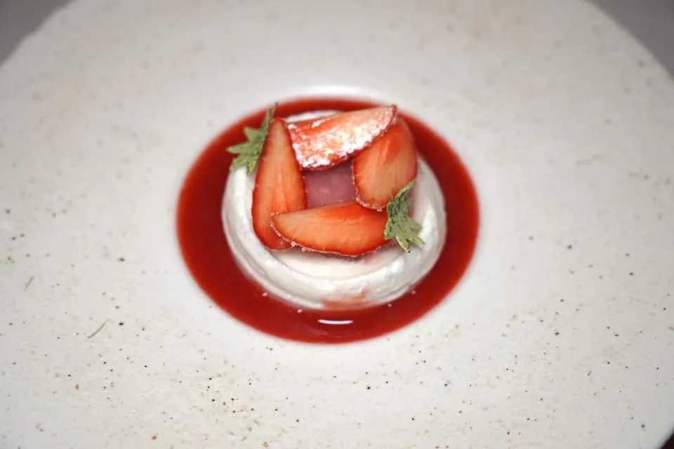Strawberry Floating island, candied fruit, coulis จากนั้นพนักงานจะมาเทราด Strawberry Coulis เพื่อให้องค์ประกอบตรงกลางกลายเป็น Floating Island ด้านบนท็อปด้วย Candied Strawberry ซึ่งจะมีเลเยอร์กรอบ ๆ ช่วยเพิ่มมิติทางเนื้อสัมผัส (18/20)