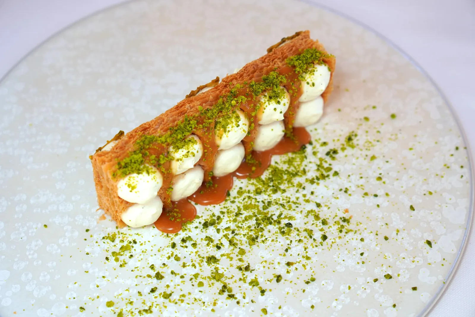 Millefeuille Baumaniere's tradition, “Modernity” light cream with Madagascar vanilla, pistachio florentine and vanilla ice cream แป้งพัฟแพสทรี่บางกรอบวางมาในแนวตั้ง ด้านข้างประดับตกแต่งด้วยครีมที่ผสมผสาน Crème Supérieur Gastronomique 35% Président เข้ากันกับ Madagascar Vanilla จนได้เนื้อสัมผัสที่ครีมมี่ หอม มัน (19/20)