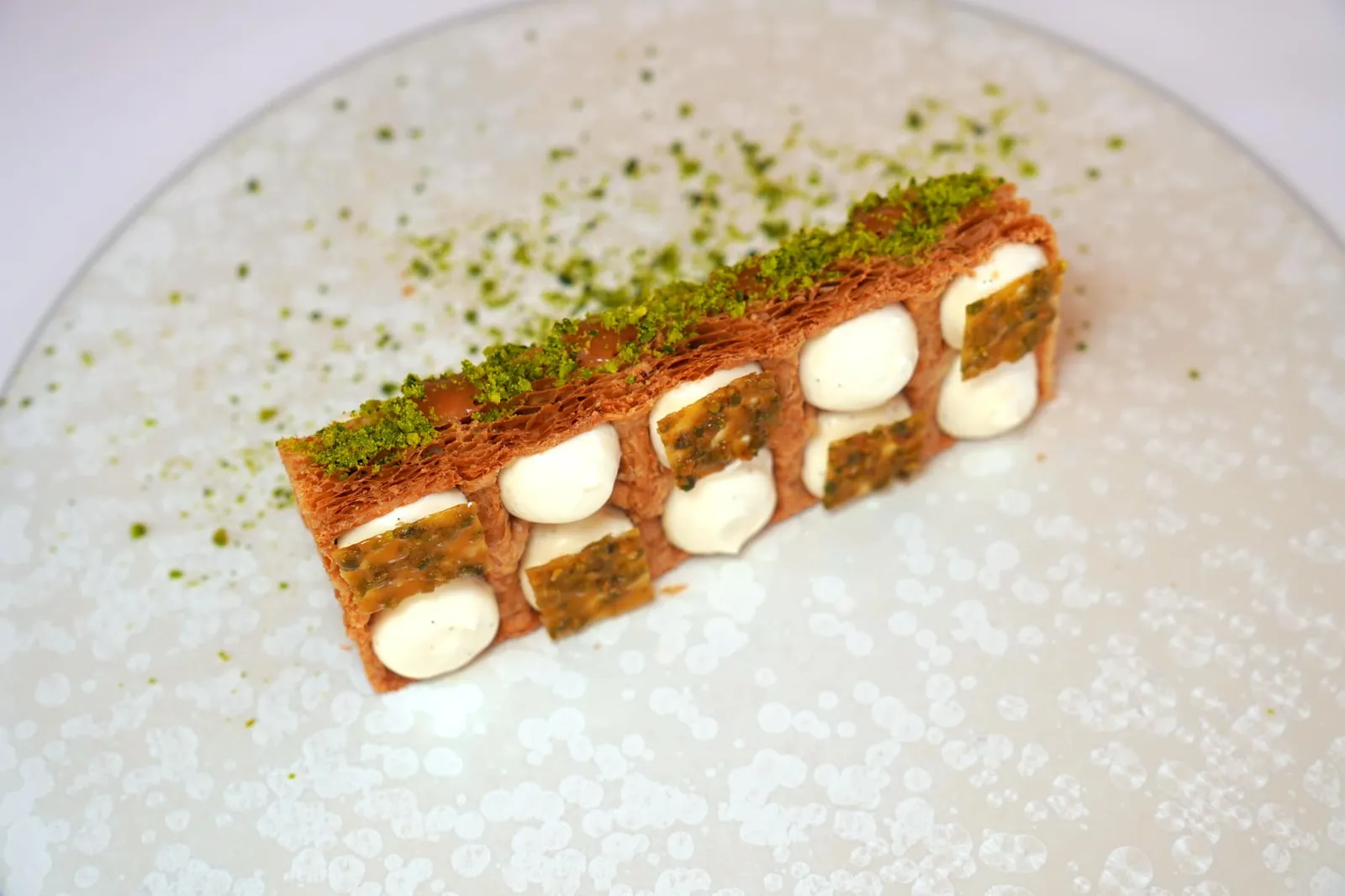 Millefeuille Baumaniere's tradition, “Modernity” light cream with Madagascar vanilla, pistachio florentine and vanilla ice cream จากนั้นเสริมด้วยรสชาติอันเข้มข้นของ Salted Butter Caramel และอโรมาของ Pistachio Florentine มองเห็นเป็นองค์ประกอบสีเขียวที่ด้านบน (19/20)