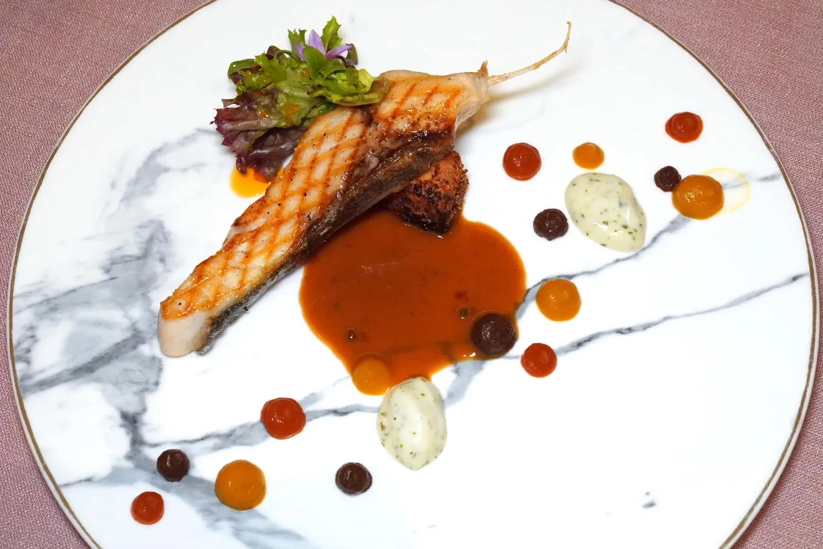 BARBECUEWild catch Giant trevally, bearnaise, ratatouille and pepper sauceเมนคอร์สจานหลักเชฟตั้งใจนำเนื้อปลามาเตรียมเลียนแบบเนื้อ เชฟเลือกใช้ปลากะมงพร้าวย่างแบบบาบีคิวจนสุก ด้านล่างรองด้วยเนื้อปลาที่คลุกเคล้ากับเครื่องเทศ จากนั้นเสิร์ฟมากับซอส 5 อย่าวคือซอสเห็ดย่างสีน้ำตาล ซอสราตาตูยสีส้ม ซอสพริกหวานสีเหลือง และซอสแบร์เนสสีขาวอ่อน จากนั้นพนักงานจะเทซอสพริกไทยเขียวลงไปใฟ้ความเข้มข้น นอกจากนี้ยังมีสลัดเสิร์ฟมาเป็นช่อบูร์เก้อีกด้วย (14/20)