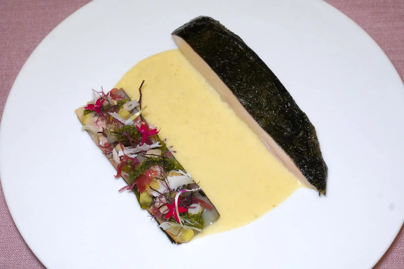 STEAMEDRed label Chicken, leek, seaweed beurre blancคอร์สนี้เชฟตั้งใจเลียนแบบคอร์สปลาแต่เปลี่ยนมาเสิร์ฟเป็นเนื้อไก่ชิ้นโตที่ผ่านการ Slow-Cooked เพื่อคงไว้ซึ่งความฉ่ำของเนื้อ จากนั้นโปะผิวด้านบนด้วยชิ้นสาหร่ายโนริจนและดูคล้ายหนังปลา ข้าง ๆ กันคือกระเทียมต้นย่างยัดไว้ด้วยสาหร่ายโนริ สาหร่ายพวงองุ่น ขาไก่ และหอยหลอด จากนั้นเทซอสเบลอบลองก์ที่มีส่วนผสมของสาหร่ายลงไปตรงกลางช่วยเชื่อมเนื้อสัมผัสและเติมแต่งรสชาติให้สมบูรณ์แบบ (15/20)