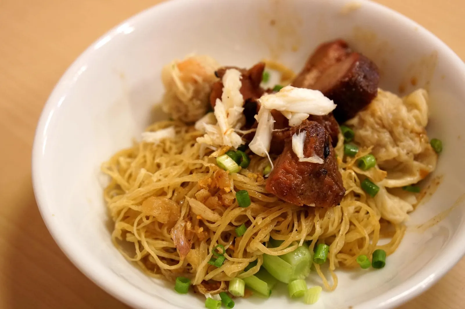 บะหมี่เกี๊ยวหมูกรอบ + ปู (100) Egg noodles with shrimp wonton, crispy pork and crab meat บะหมี่เกี๊ยวกุ้ง ทานคู่กับหมูกรอบสูตรพิเศษ โดยหมูกรอบที่นี่จะต่างกับหมูกรอบทั่วไป เพราะหนังไม่กรอบ ออกจะคล้ายหมูแดงรมควันมากกว่า ขอบของหมูจะแข็งกว่าหมูแดงเล็กน้อย แต่ตรงกลางจะนุ่ม และไม่มีส่วนที่กรอบเลย ถึงจะแปลกๆที่เรียกว่าหมูกรอบ แต่เอาเป็นว่ามันอร่อยมากเป็นใช้ได้ หอม มีรสหวานพอดี ทานกับเนื้อปูสดๆ ที่แกะมาเรียบร้อย ซึ่งนุ่ม หอมกลิ่นปูมากๆ ทำให้สองอย่างนี้ตัดเนื้อสัมผัสกันได้ลงตัวสุดๆ บะหมี่ก็เส้นเหนียวนุ่ม ผักลวกมาสุกพอดี ไม่มีรสขมเลย ถือว่าอร่อยมาก ใครมาที่นี่เราเเนะนำให้สั่งจานนี้ คุ้มราคาแน่นอน (14/20)