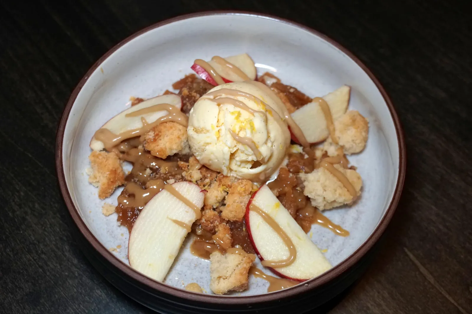 APPLE CRUMBLE (220++) Apple Textures / Marinated Longan / Lemon / Caramel / Vanilla Ice Cream ขนมหวานที่ดีที่สุดขอยกให้ “แอปเปิ้ลครัมเบิ้ล” เชฟนำแอปเปิ้ลมาทำออกเป็นหลากหลายองค์ประกอบทเสิร์ฟมาคู่กับลำไยรสหวาน ซอสคาราเมลหอมเข้มข้น ครัมเบิ้ลกรอบ และวานิลลาไอศกรีม (13/20)