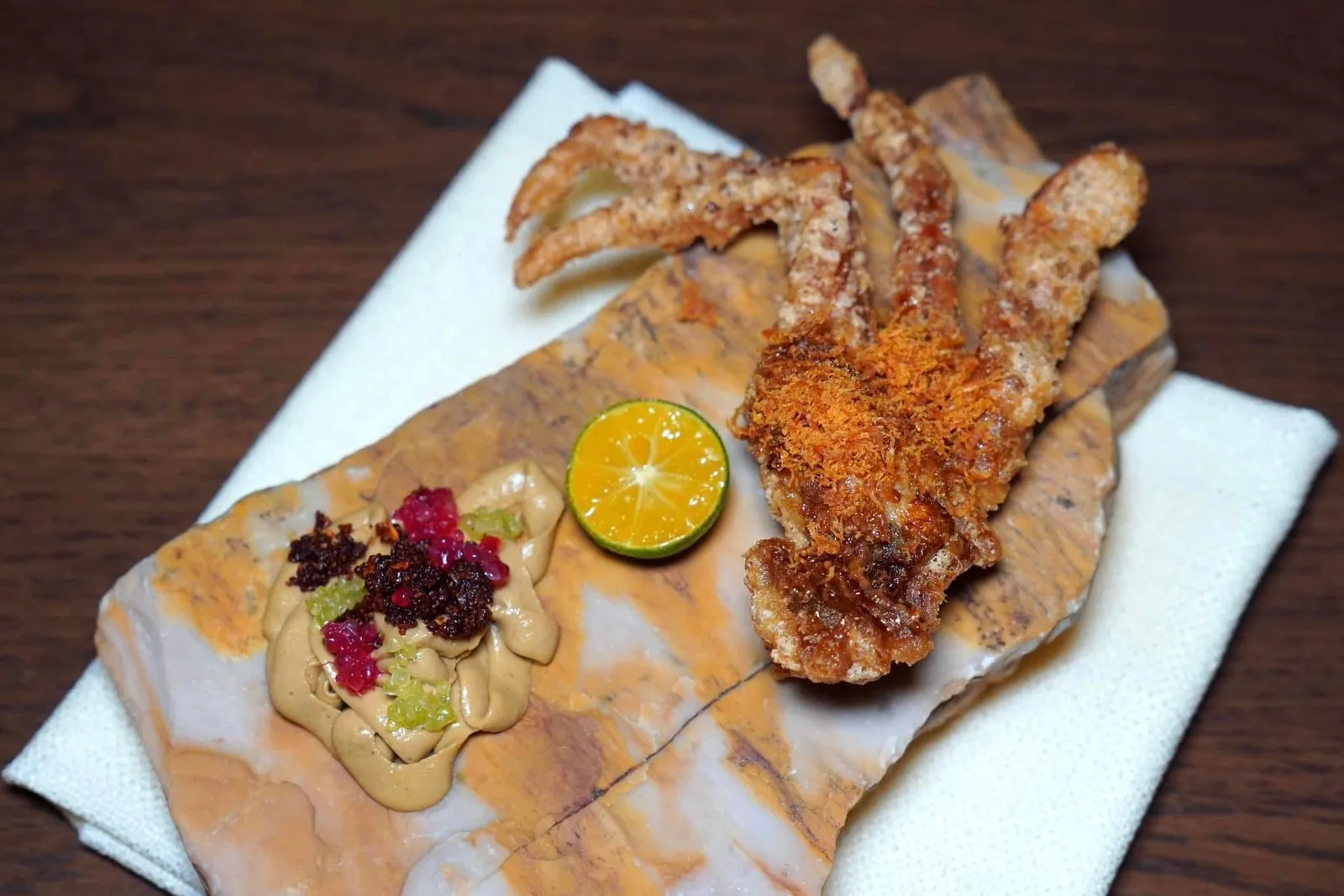 “Fried Softshell Crab, ปูนิ่มทอด” ทางร้านได้เฟ้นหาปูนิ่มแบบเป็น ๆ จากจังหวัดจันทบุรีปรุงแต่งรสด้วยน้ำปูและกะทิเพื่อให้มีความกรอบที่พอเหมาะตัดกันกับความนิ่มของชิ้นปู ด้านบนคือเนื้อปูฟูหอมหวาน ข้าง ๆ กันคือมันปูนาน้ำพริกข่าปรุงแต่งด้วยความเปรี้ยวจากมะนาวนิ้วมือเตรียมออกมาเป็นคาเวียร์จิ๋ว วิธีบิมให้บีบน้ำส้มจี๊ดลงไปบนเนื้อปูเพื่อดึงรสชาติของปูให้โดดเด่นยิ่งขึ้น (15/20)