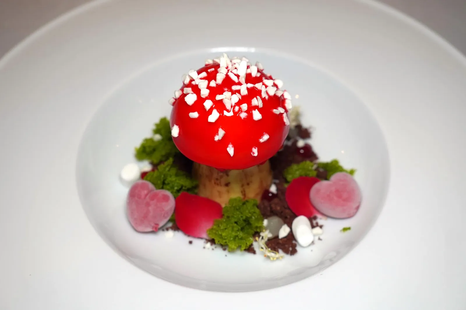 FOREST MUSHROOM Vanilla Mousse | Yogurt Mousse | Pistachio Sponge Cake | Chocolate Crumble | Cherry Mousse | Cherry & Yuzu Gel | Marshmallow Forest Mushroom เป็นของหวานที่จัดเสิร์ฟเป็นครั้งแรกในเซ็ตเมนูวันวาเลนไทน์ตั้งแต่ร้านสาขาเดิม เชฟ Henk นำเสนอออกมาเป็นขนมรูปเห็ดมองจากภายนอกมีสีสันสวยงาม ส่วนโดมของเห็ดทำมาจาก White Chocolate เกลซให้เป็นสีแดงด้วยองค์ประกอบของเชอร์รี่ ด้านในบรรจุวานิลและมูสโยเกิร์ตเนื้อเนียน ส่วนต้นของเห็ดทำมาจากเมอแรงก์กรอบ ด้านล่างเป็นช็อกโกแลตครัมเบิ้ลชวนนึกถึงดินในผืนป่า ยังมีสปองเค้กสีเขียวที่เตรียมมาจากถั่วพิสตาชิโอ มาร์ชแมลโล่ว์นุ่มหนึบ เจลรสเปรี้ยวทำมาจากยูซู ปิดท้ายด้วยการวางเชอร์รี่รูปหัวใจลงไป ขอแนะนำให้รับประทานหลาย ๆ องค์ประกอบพร้อมกันเพื่อให้ได้เนื้อสัมผัสและรสชาติที่หลากหลาย (15/20)