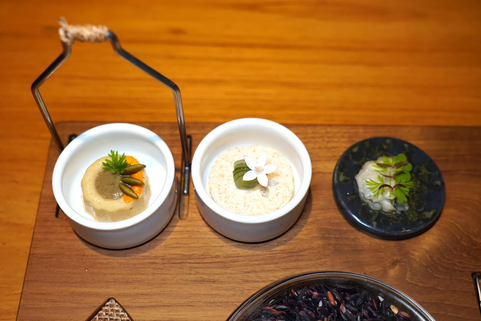 PINTOKUM DOI RICE FROM CHIANG MAI | PUMPKIN PELL | PUMPKIN SEED PRALINE | CARAMELIZED WILD HONEY | BETONG CHICKEN | BURNT LEEK | CABBAGE | CORN SPROUTSชิ้นขนมปังเตรียมมาจากข้าวก่ำดอยจากจังหวัดเชียงใหม่จับคู่มากับองค์ประกอบที่เตรียมมาจากเมล็ดฟักทองพราลีนผสมผสานกันกับบราวน์บัตเตอร์ที่มีความหวานของน้ำผึ้งป่าเคี่ยว ถัดมาคือไก่ผัดกระเทียมที่ได้จากการผสมผสานเนยฝรั่งเศสเข้ากันกับกระเทียมต้นย่าง เชฟใส่หนังไก่ทอดลงไปด้วย ด้านบนมีความเปรี้ยวที่ได้จากผักดอง สุดท้ายคือผักส้มที่เตรียมมาจากกะหล่ำปลีและโคนต้นหอม จากนั้นท็อปด้วยเจลน้ำดองเข้มข้นนั่นเอง (14/20)