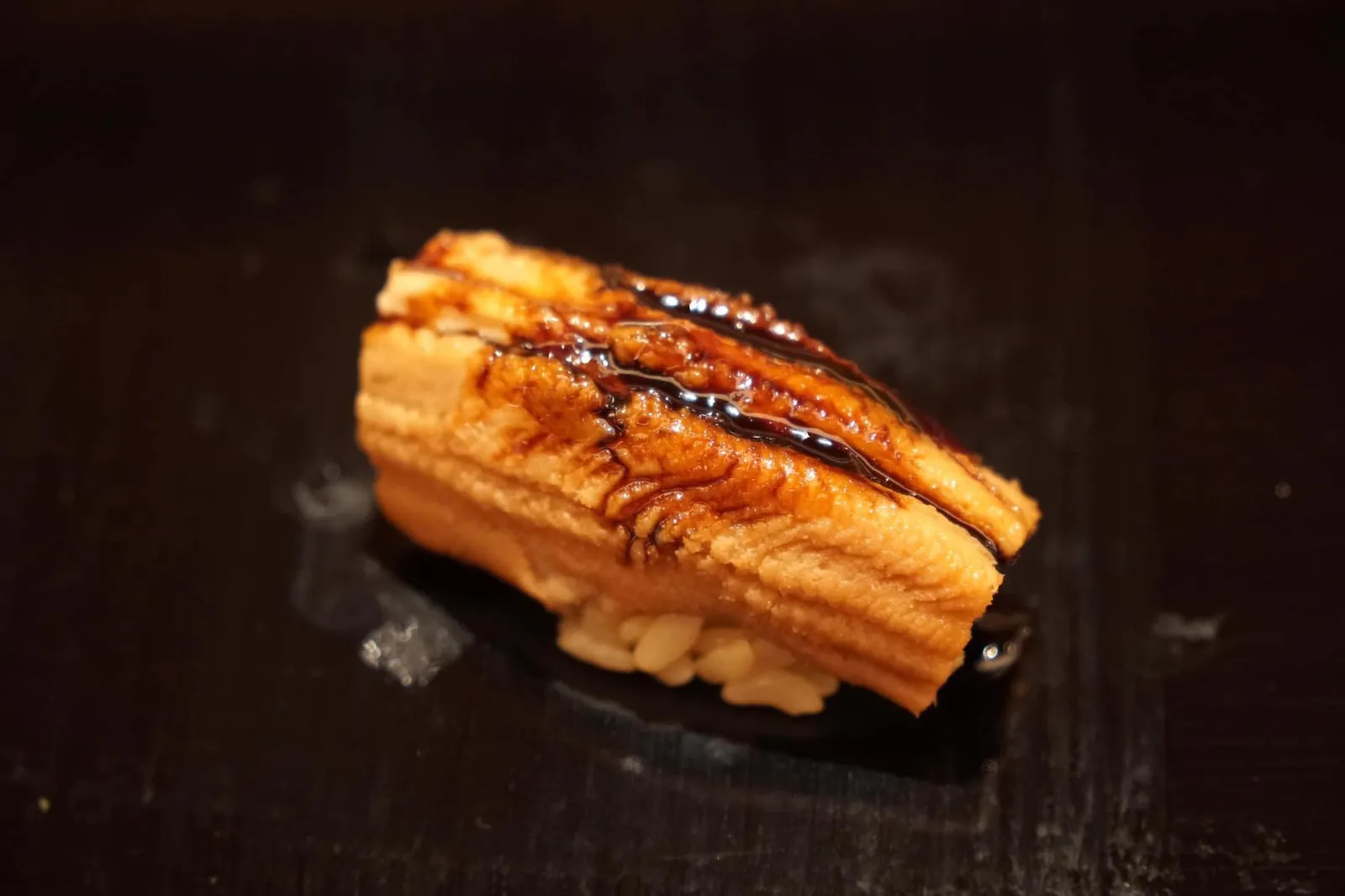 Anago นิงิริคำสุดท้ายคืออีกหนึ่งทีเด็ดหมัดหนักประจำมื้อนี้ “อนาโกะ” หรือปลาไหลทะเล สิ่งที่ทำให้เราทึ่งเลยคือปลาไหลคำนี้พอทานเข้าไปแล้วเพียงใช้ลิ้นแตะเบาๆ เนื้อปลาจะละลายในปากทันที เราเคยทานปลาไหลทะเลมามากทั้งจากร้านซูชิระดับมิชลินเพลทจนถึงระดับมิชลินสตาร์ แต่ไม่เคยมีที่ไหนทำเนื้อปลาไหละลายในปากได้ขนาดนี้ ทั้งรสชาติของซอสยังเข้มข้นเข้ากันได้ดีกับเนื้อปลา คำนี้ถือว่าน่าอัศจรรย์มากๆ (20+/20)