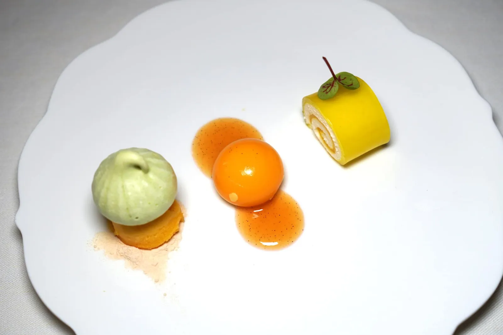 Citrus composition with passion fruit - sorbet ของหวานจานแรกคือการนำเสนอผลไม้นำพวกซิตรัสออกมาในหลากหลายรูปแบบเริ่มองค์ประกอบฝั่งซ้ายมือคือซอร์เบท์เสาวรสท็อปด้านบนด้วยมาการองสีเขียวเตรียมมาจากถั่วพิสตาชิโอ้ ตรงกลางคือ Orange Sphere ทรงกลมบรรจุมูสส้มนุ่ม ๆ สุดท้ายคือเลมอนที่พันม้วนกับครีมเป็นโรลขนาดจิ๋วนั่นเอง (17/20)