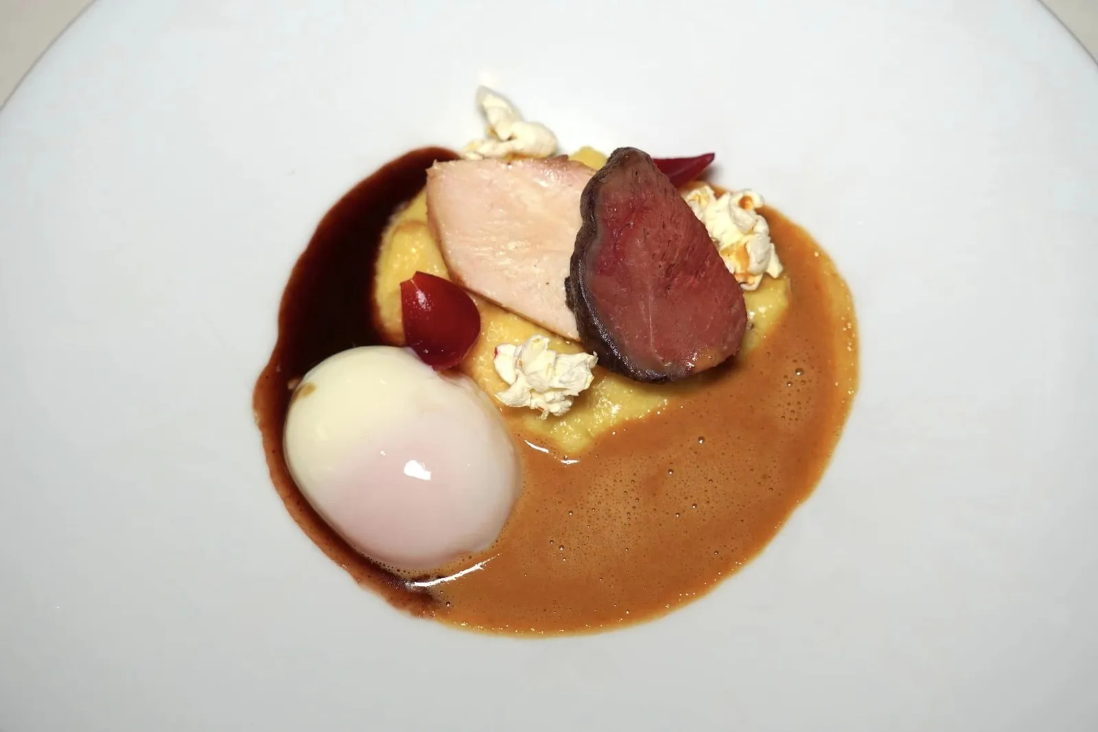 Duo of Bresse - Pigeon and Breton poussin with corn - texture, red wine - pearl onions and albufera sauce คอร์สนี้เชฟให้ชื่อว่า Duo of Bresse อันเนื่องมาจากวัตถุดิบหลักของจานคือเนื้อนกพิราบและเนื้อไก่ซึ่งเป็นวัตถุดิบขึ้นชื่อของเมือง Bresse ในประเทศฝรั่งเศสนั่นเอง ด้านล่างรองด้วย Polenta ข้าวโพดนุ่ม ๆ และป็อบคอร์นกรอบ ๆ นอกจากนี้ยังมีหอมแดงหองในไวน์แดงให้ความกรอบและไข่ไก่ Onsen ที่พร้อมจะแตกไหลเยิ้มออกมาเป็นลาวา สำหรับซอสนั้นเชฟเลือกนำแชมเปญไป Reduction หรือเคี่ยวจนงวดจับคู่มากับ Port Wine Jus รสชาติเข้มข้น (17/20)