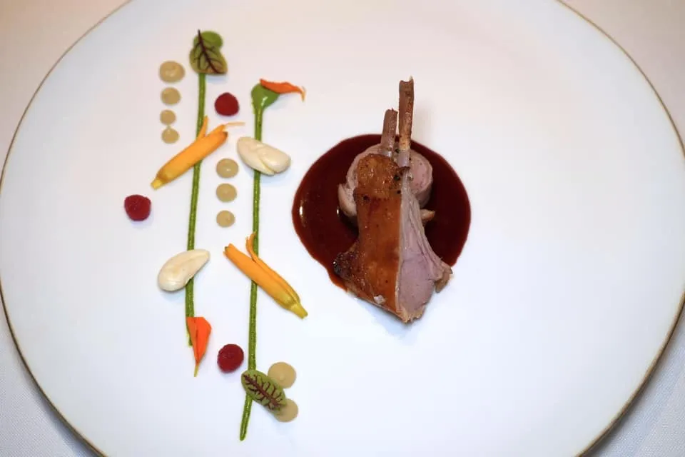 SUCKLING LAMB, HERBS, GARLIC AND ANCHOVIES. From our farm in Extremadura เนื้อลูกแกะยังไม่หย่านมจากฟาร์มของเชฟในเมือง Extremadura ทางตะวันตกของปนะเทศสเปน เชฟเลือกใช้ส่วนหัวไหล่และซี่โครงนำไปปรุงให้สุกช้า ๆ เพื้อให้เนื้อยังคงความฉ่ำเอาไว้ได้มากที่สุด ด้านล่างคือซอส Jus รสชาติเข้มข้น องค์ประกอบฝั่งซ้ายมือคือถั่วอัลมอนด์, ดอกไม้เคียง, กระเทียม, บ๊วยแดง และองค์ประกอบของแองโชวี่ ส่วนซอสสีเขียวเตรียมมาจากสมุนไพร Aromatic Herbs ผสมกันกับโยเกิร์ต (18/20)