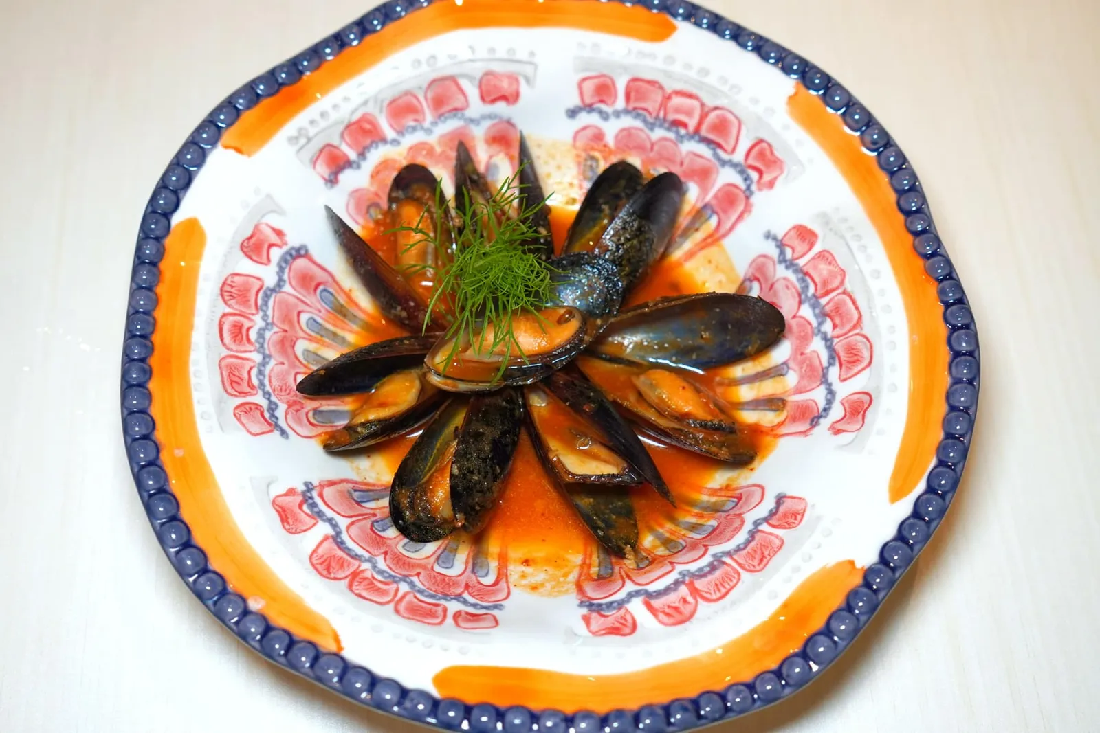 MUSSEL STEWED Black Mussels, White Wine Spicy Tomato Sauce หอยแมลงภู่อบกับไวน์ขาวจนสุก เคี้ยวแล้วมีความนุ่มหนึบ ไม่มีกลิ่นคาว ส่วนซอสสีแดงด้านล่างมีความเปรี้ยวจากมะเขือเทศปนกับความเผ็ดเล็กน้อย (12/20)