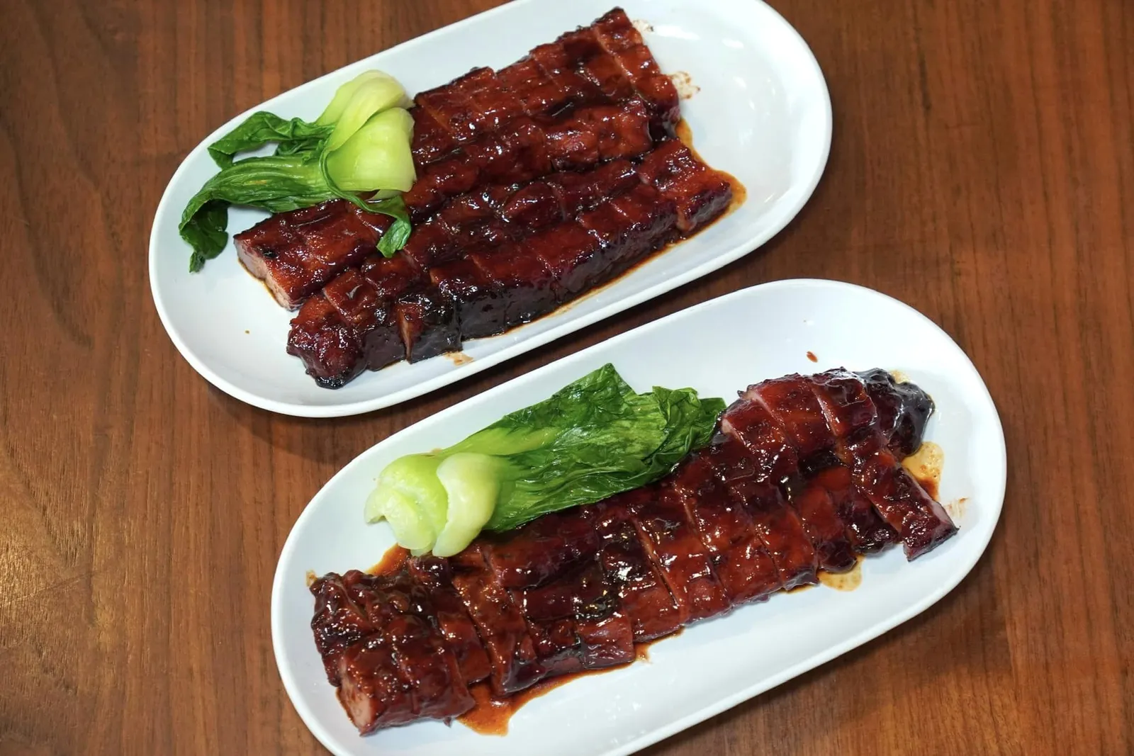 หมูแดงฮ่องกงส่วนสันคอ 500 กรัม (450) HK Roasted Pork (Boston Butt) เริ่มต้นกันที่หมูแดงซึ่งเป็นเมนูชูโรง ความลับของเมนูนี้คือการนำเนื้อหมูไปตัดเป็นชิ้นยาว ๆ หมักกับเครื่องเทศนานถึง 48 ชั่วโมงจนซึมเข้าเนื้อ จากนั้นนำมาย่างสลับกันกับการนำขึ้นมาชุบน้ำย่างแบบนี้ถึง 4 รอบเพื่อให้รสชาติมีความเข้มข้น ขั้นตอนสุดท้ายคือการนำมาทาแบะแซแล้วทอร์ชไฟเพื่อบริเวณผิวมีความหวานและหอมมากยิ่งขึ้น สำหรับใครที่เลือกชิมส่วนสันคอจะพบกับอัตราส่วนไขมันรวมไปถึงเนื้อสัมผัสที่สู้ฟันน้อยกว่าส่วนสันนอก (13/20) หมูแดงฮ่องกงส่วนสันนอก 500 กรัม (500) HK Roasted pork (Pork Belly) ส่วนเรานั้นประทับใจเนื้อหมูส่วนสันนอกที่มีอัตราส่วนไขมันเยอะและฉ่ำมากกว่า (14/20)