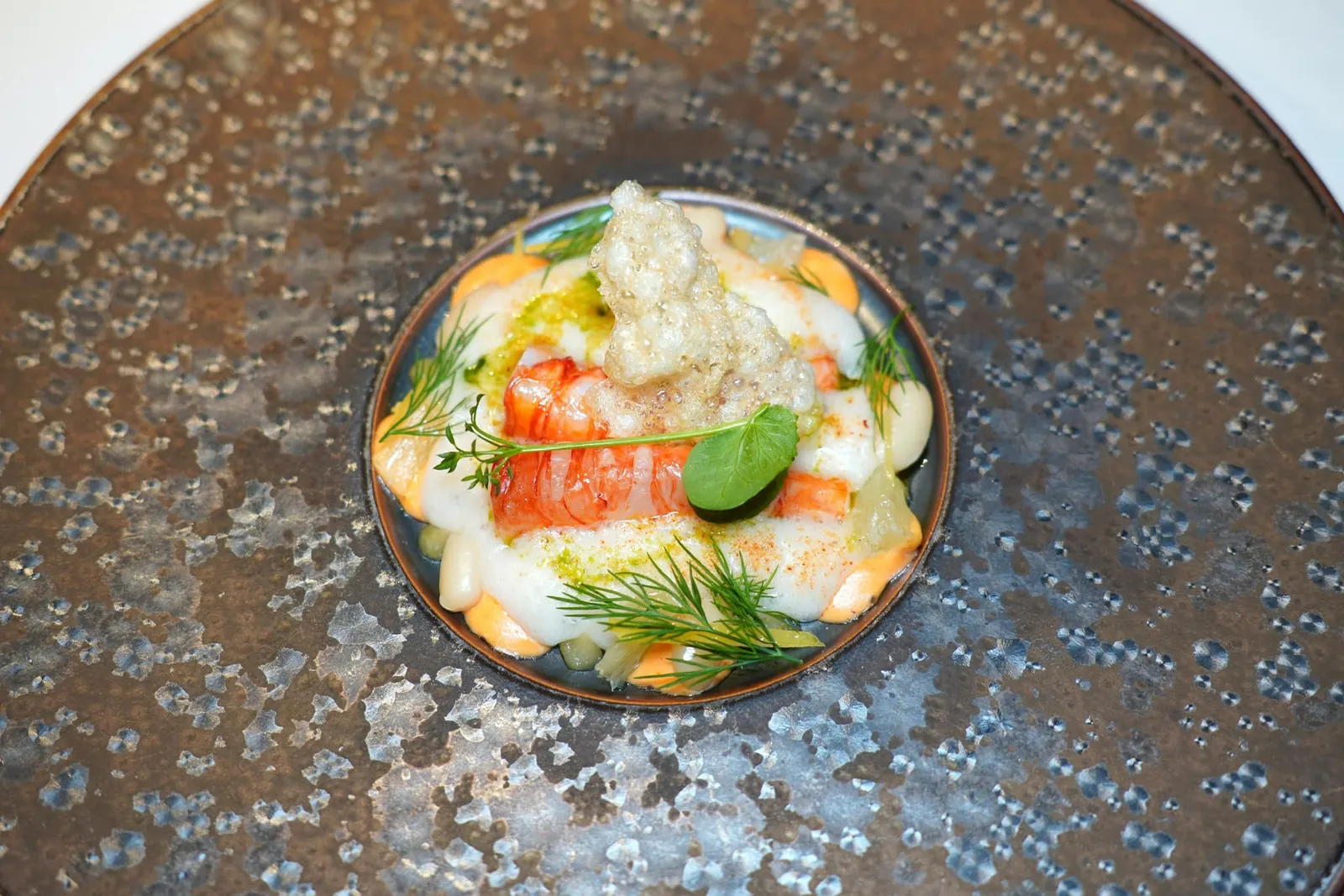 Red Prawn • Zolfino Bean • Lemon กุ้งแดงย่างให้รสชาติหวานโดยธรรมชาติ เนื้อสัมผัสเด้งที่ผิวนอกแต่ตรงกลางยังคงไว้ซึ่งความละมุน รอบ ๆ คือครีมสีขาวที่เตรียมมาจากถั่ว Zolfino รวมไปถึงชิ้นถั่วเองให้เนื้อสัมผัสที่สู้ฟัน ถั่วชนิดนี้เจริญเติบโตได้ทั่วไปในแถบ Tuscany นอกจากนี้ยังมีซอส Bisque สีส้มช่วยแต่งแต้มรสชาติและความเข้มข้น ทั้งนี้เรายังสามารถได้ถึงรสเปรี้ยวและกลิ่นหอมของเลมอน ด้านบนคือ Tapioca Chip กรอบ ๆ ช่วยเพิ่มมิติทางเนื้อสัมผัส (18/20)