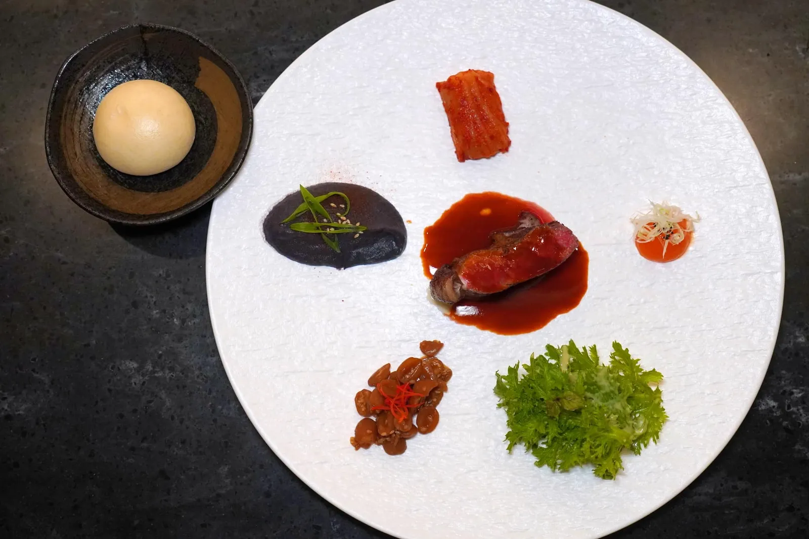 SMOKED GALBI 스모그 갈비 Galbi หรือเนื้อวัวส่วน Striploin Marble Score 4-5 เสิร์ฟมาที่ความสุกระดับ Medium Rare จากนั้นราดด้วยซอส Red Kimchi Beef Jus เข้มข้น ข้าง ๆ กันคือองค์ประกอบเคียง 5 ชนิดและ Bun หรือขนมปังนุ่ม ๆ ให้ฉีกหรือปาดไปควบคู่กัน (15/20)