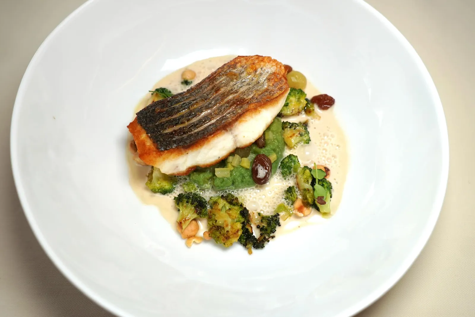 Le filet de bar, brocoli et noisettes du Piémont, vierge automnale ปลา Sea Bass เสิร์ฟมาเป็นฟิเลท์ เชฟนำไปย่างจนหนังกรอบ ด้านล่างรองด้วยบล็อคโคลี่และถั่ววอลนัทจากแคว้น Piedmont ในประเทศอิตาลี รอบ ๆ คือซอสครีม (16/20)