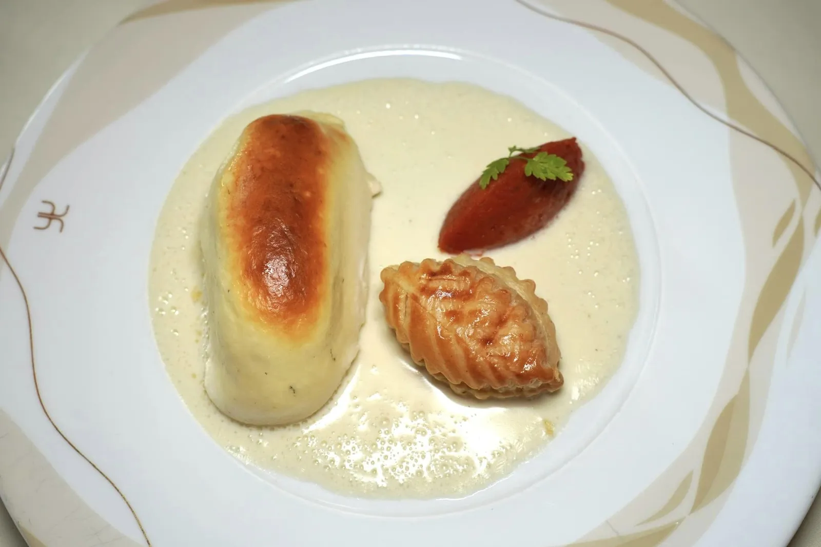Le saumon soufflé « Auberge de l'Ill » Salmon Soufflé « Auberge de l'Ill » เป็นเมนูระดับตำนานของเชฟ Paul Harberlin เชฟเสิร์ฟฟิเลท์ของปลาแซลมอนมา รอบ ๆ คือ Mousseline ที่มีส่วนผสมของเนื้อปลาและไข่ขาวให้เรื้อสัมผัสที่นุ่ม ฟู ละมุนลิ้น ทั้งนี้เนื้อสัมผัสที่แตกต่างของทั้งคู่สามารถสร้างมิติที่ละเอียดอ่อนและมีกลิ่นหอมเย้ายวนใจ จากนั้นราดด้วยซอสครีมที่เตรียมขึ้นมาจากน้ำสต๊อกปลา, จันทน์เทศ (Nutmeg) และไวน์ขาว Reisling แห่งแคว้น Alsace ให้ความหอมมันและเปรี้ยวเบา ๆ จากเลมอน อีกฝั่งหนึ่งคือมะเขือเทศสับหยาบช่วยเติมแต่งรสชาติเปรี้ยวตัดกันอย่างลงตัว ข้างกันยังมี Fleurons มีลักษณะเป็นพัฟแพสทรี่เสิร์ฟมาเป็นรูปใบไม้สวยงาม (19/20)