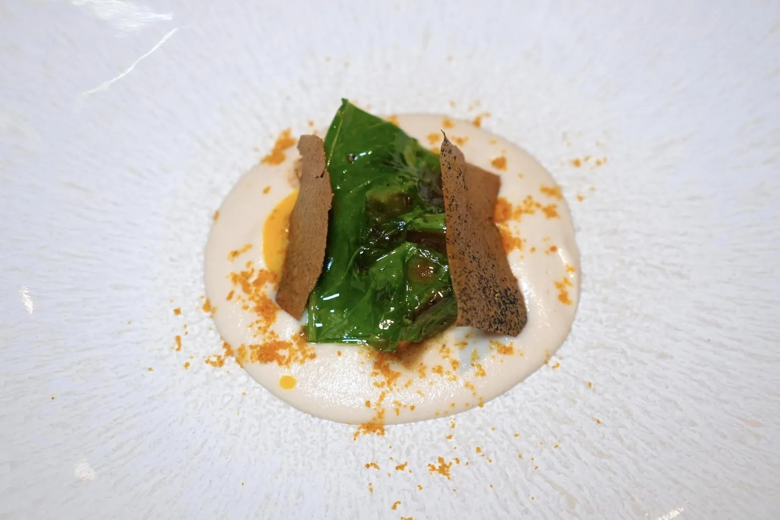 Turbot fillet with juniper, almonds, chard, yolk cream and bottargaปลาเทอร์บอทแล่เป็นชิ้นฟิเลท์ปรุงสุกในกระทะกับเนยและจูนิเปอร์จนหอมให้เนื้อสัมผัสที่สู้ฟันพอเหมาะ รอบ ๆ คือครีมอัลมอนด์รสหวานและครีมไข่แดงให้ความครีมมี่ ด้านบนคือใบ Chard วางมาขนาบข้างด้วยแผ่นกรอบที่เตรียมมาจากหนังของปลาเทอร์บอท ส่วนผงสีส้มรอบ ๆ คือไข่ปลา Bottarga จากปลา Mullet นั่นเอง รสชาติโดยรวมถือว่ามีความหวานของอัลมอนด์โดดเด่นและความครีมมี่ที่ได้จากครีมไข่แดงจนอาจกลบรสชาติขององค์ประกอบอื่น ๆ ไปบ้าง (17/20)
