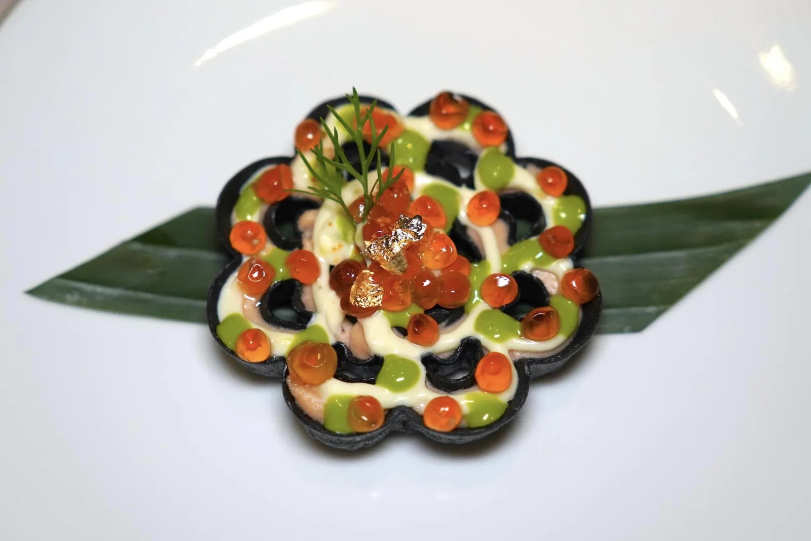 CAVIAR BÁNH NHÚNGWaffle cake, salmon roe, smoked salmon, crème fraicheCaviar Bánh Nhúng เป็นเมนูที่ได้รับแรงบันดาลใจมาจากวาฟเฟิลเค้กที่พบได้ตามร้านอาหารริมทางในตลาดของประเทศเวียดนาม เขฟนำเสนอมาโดยใช้เทคนิคการเตรียมแป้งทาร์ตแบบฝรั่งเศสแต่เปลี่ยนถ้วยทาร์ตปกติให่เป็นวาฟเฟิลรูป Rosette สรดำเตรียมมาจากแป้งข้าวและไข่ ตามช่องเติมแต่งด้วย Crème Fraîche เคล้าไปกับเนื้อปลาแซลมอนรมคว้น จากนั้นจบด้วยการใส่เจลผักชีลาวและไข่ปลาแซลมอนลงไปด้านบนให้อโรมาที่ฉุนและกลิ่นอายของทะเลมาบาลานซ์กันได้อย่างพอเหมาะ (15/20)