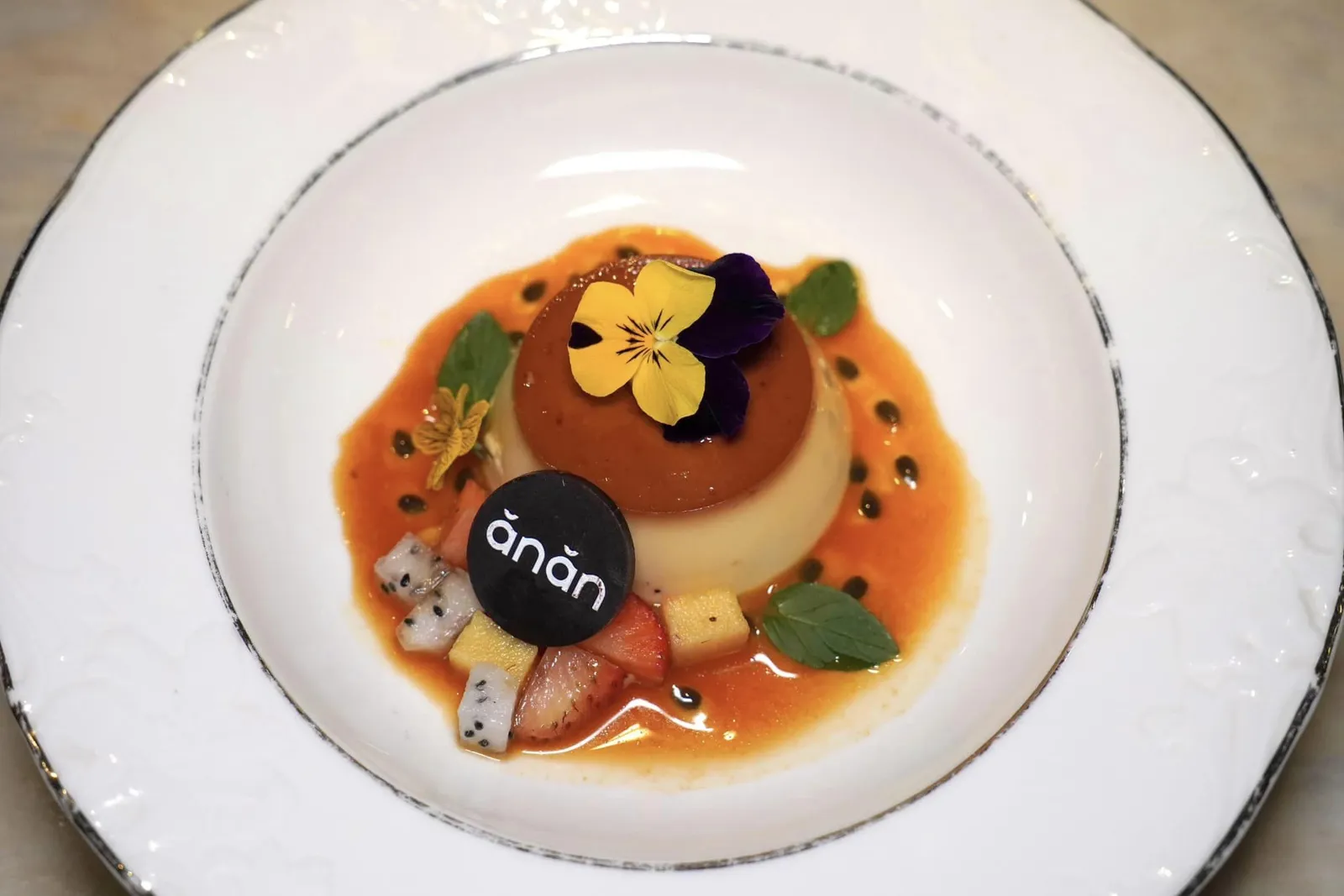 CRÈME CARAMEL (230,000 VND++)Caramel custard, Đà Lat strawberry, passion fruit, mintขนม Crème Caramel มีลักษณะเป็นคัสตาร์ดเนื้อเนียนละมุน เสิร์ฟมาคู่กันกับสตรอว์เบอร์รี่ Đà Lat และซอสเสาวสรสเปรี้ยว นอกจากนี้ยังมีความสดชื่นของใบมิ้นต์อีกด้วย (14/20)
