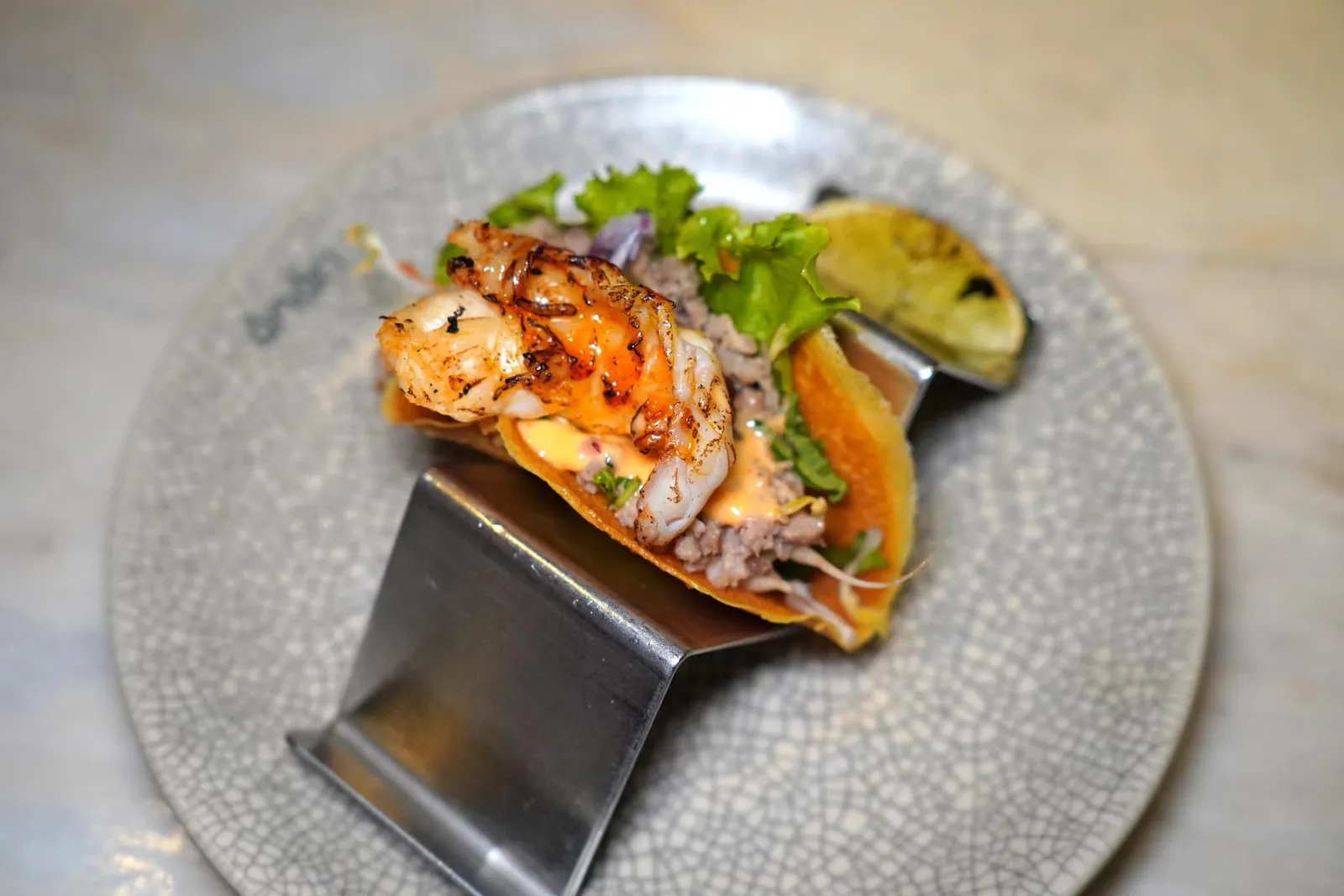 RIVER PRAWN BÁNH XẺO TACOPrawn, pork belly, fresh herbsBánh Xèo เป็นเมนูที่มีต้นกำเนิดมาจากเมือง Huế ในแถวเวียดนามตอนกลางโดยอาศัยเทคนิคที่ปรับปรุงมาจากการยึดครองของประเทศฝรั่งเศสในยุคโคโลเนียล เครปที่มีแป้งกรอบทำจากข้าวผสมกันกับขมิ้นจนได้สีเหลืองโดดเด่นโดยเชฟ Peter Cuong Franklin ได้เปลี่ยนจากแป้งทรบแบนราบ มาเป็นทาโก้เพื่อให้มีความร่วมสมัยและรับประทานได้ว่าย ตรงกลางบรรจุหมูสามชั้น เนื้อกุ้งแม่น้ำ ซอสถั่วลิสงรสเด็ด และสมุนไพรนานาชนิด พนักงานแนะนำให้แต่งเติมรสเปรี้ยวด้วยมะนาวย่างได้เองตามใจชอบ (15/20)