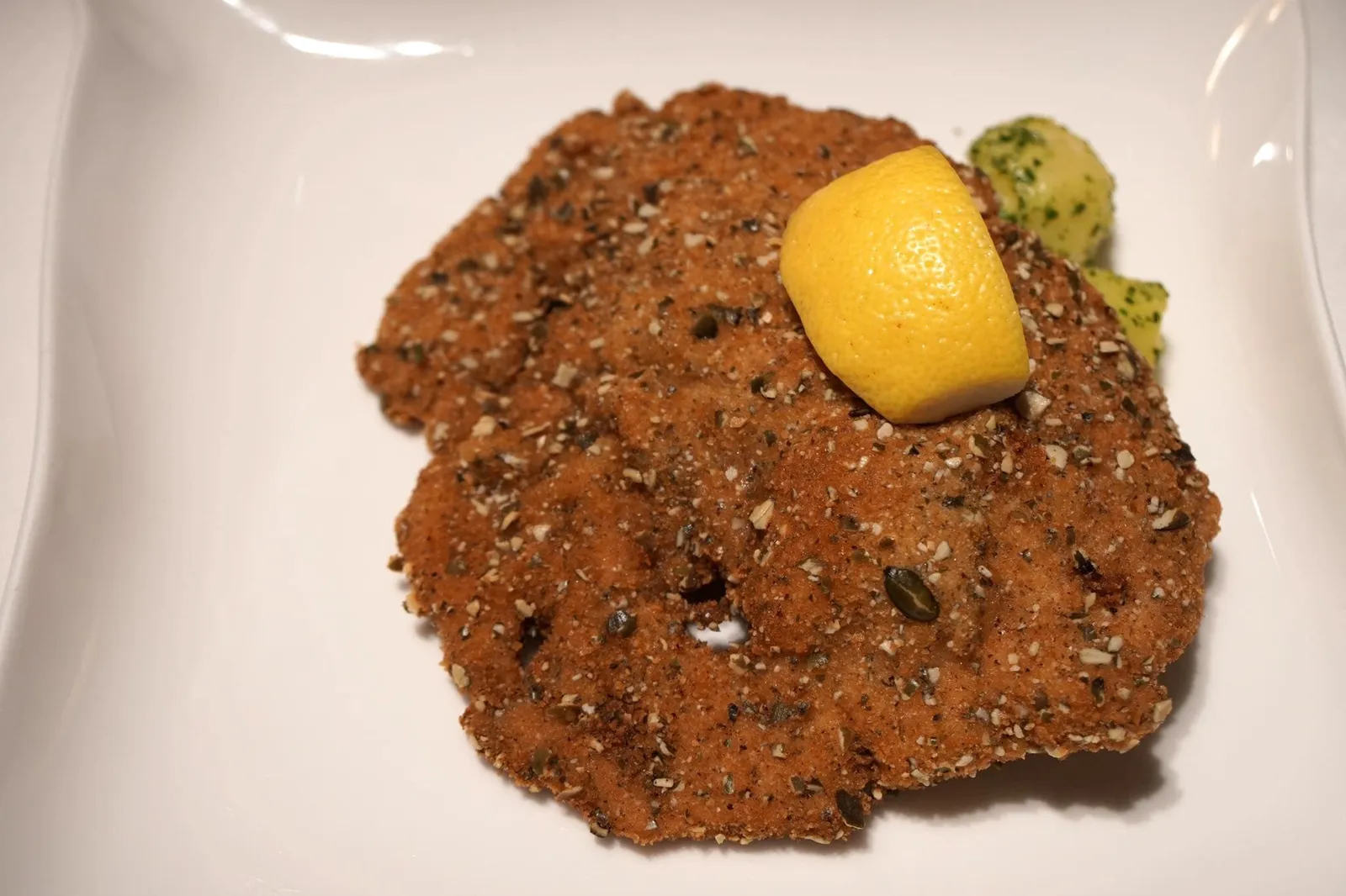 - Landschwein (14 EUR)Gebackenes Kürbiskern-Schnitzel vom niederbayerischen Schweinerücken mit Petersilien-Erdäpfel & Preiselbeeren🍋 ชนิทเซลหรือหมูทอดเยอรมัน เมนูคอมฟอทฟู้ดที่ทุกคนต้องลองชิมเวลามาเที่ยวเยอรมัน แต่ในร้านระดับมิชลินสตาร์ ชนิทเซลถูกยกระดับให้มีรสชาติอร่อยมากขึ้นไปอีกขึ้น จากการแผ่นหมูที่ทำออกมาบางเท่ากัน คลุกกับแป้งบางๆและสมุนไพร ทอดจนกรอบ มีสีเหลืองอร่าม ดูน่ากิน กรอบนอก นุ่มใน ยังคงความฉ่ำของเนื้อหมูไว้ได้อย่างดี รองด้านล่างด้วยมันฝรั่งเนื้อนุ่มคลุกกับพาสลีย์ ก่อนทานบีบเลมอนราดลงไป รสเปรี้ยวของเลมอนจะตัดความมันของหมูทอดออก อร่อยมากจริงๆ
