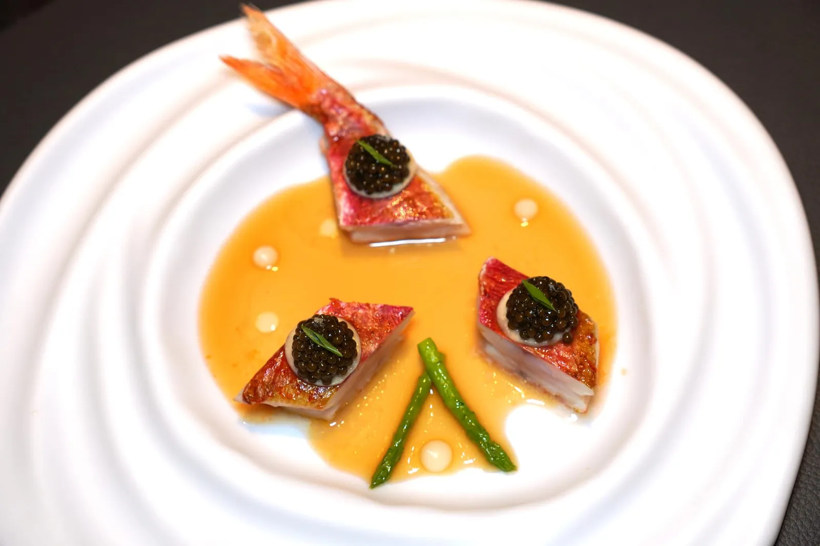 Il.Poached red mullet with "kaviari kristal" caviar, Banana and Cardamom-Riesling decoctionปลา Red Mullet ที่ผ่านการ Poached จนสุกสังเกตได้จากเนื้อสัมผัสที่สู้ฟันพอเหมาะพอดี ด้านบนท็อปด้วย Kaviari Kristal Caviar จากกรุง Paris ประเทศฝรั่งเศสเติมแต่งรสเค็มและให้กลิ่นอายของทะเล ไฮไลท์คือตัวครีมที่เตรียมมาจากกล้วยบ่งบอกถึงการจัยคู่รสชาติที่มีความแปลกใหม่และพบเจอได้ยาก เราประทับใจที่กลิ่นของกล้วยกลับผสมสามารถผสานเข้ากันกับ Caviar ได้อย่างน่าทึ่ง ซอสใส ๆ รอบ ๆ เตรียมมาจาก Cardamom หรือกระวานผสมกันกับไวน์ Reisling เคี่ยวจนเข้มข้น ให้รสชาติออกเปรี้ยว จากนั้นพนักงานจึงหยดน้ำมันกระวานลงไปเป็นอันพร้อมชิม (19/20)