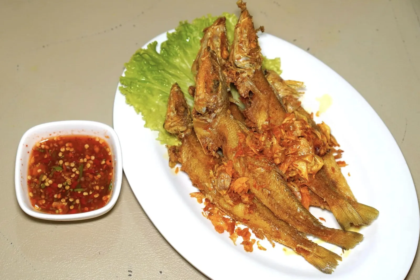 ปลาทรายทอดขมิ้น (180+)Deep-Fried Fish with Turmericปลาทรายขนาดตัวพอดีสำหรับรับประทานได้ทั้งกระดูก ทางร้านหมักปลากับขมิ้นก่อนจะทอดมาอย่างดีจนสีเหบืองสวยงามและไม่สุกจนเกินไป เนื้อปลายังคงความนุ่มตัดกันกับความกรอบของกระเทียม อย่าลืมปรุงแต่งรสชาติด้วยคือน้ำจิ้มรสเด็ดที่เสิร์ฟมาคู่กัน (13/20)