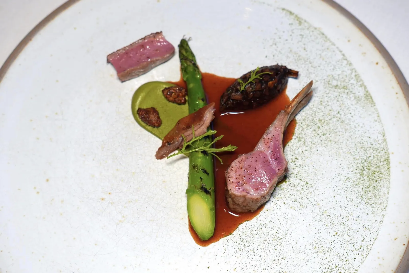 Les Landes et les Pyrénées Primeur 2024Pyrenees milk-fed lamb, Landes Asparagus and Bazas black Garlicเนื้อลูกแกะที่ยังไม่หย่านมเป็นหนึ่งในวัตถุดิบระดับโลกจากแถบเทือกเขา Pyrenees ทั้งยังเป็น Milk-fed Lamb เพียงแหล่งเดียวที่ได้รับการป้องกันและควบคุมด้วย IGP ในประเทศฝรั่งเศสอีกด้วย เชฟเสิร์ฟส่วนซี่โครงและชิ้นฟิเลท์ย่างมาสุกกำลังดีสังเกตได้จากความฉ่ำและนุ่มของเนื้อแกะ นอกจากนี้ยังมีส่วนท้องที่ผ่านการกงฟีแล้วเสิร์ฟมาคู่กันกับหน่อไม้ฝรั่งซึ่งเป็นวัตถุดิบสำคัญของภูมิภาค Landes ที่ย่างมาสุกกำลังดี ข้าง ๆ กันคือครีมถั่วพิสตาชิโอ้เสริมรสชาติหวานที่พอเหมาะ อีกฝั่งหนึ่งคือซอส Lamb Jus ที่เชฟ Infused อโรมาของมิ้นต์ลงไปด้วยเพื่อเบรกรสชาติไม่ให้เข้มโดดจนเกินไปสุดท้ายคือ Condiments ที่ผสมผสานหน่อไม้ฝรั่งเขียว, ถั่วพิสตาชิโอ, มิ้นต์, ผักชี และกระเทียมดำจากเมือง Bazas เข้าไว้ด้วยกัน (18/20)