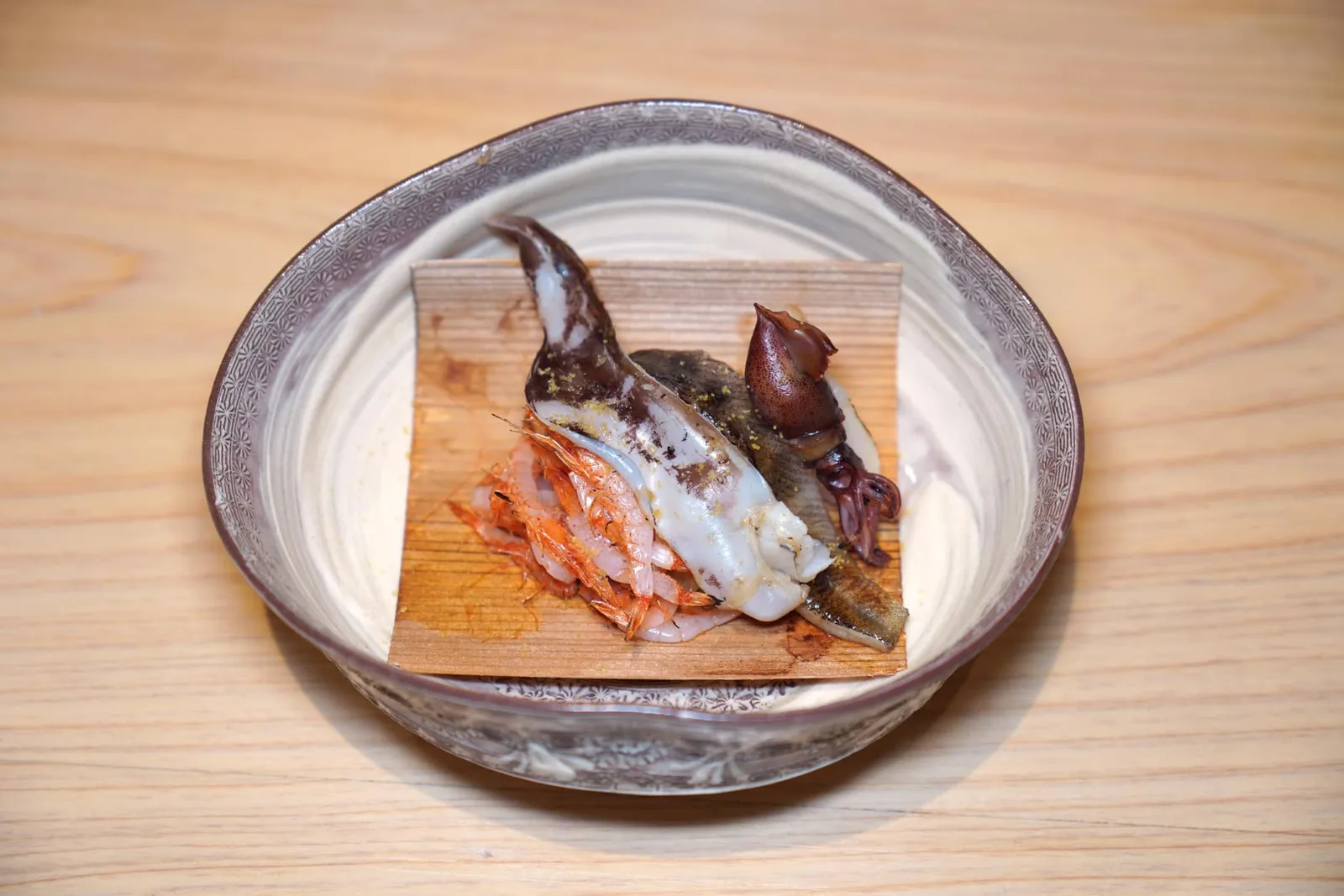 Yaki Gohanข้าวซูชิอบมาพร้อมกันกับปูขนเคกานิและอูนิ ด้านล่างคือเปลือกสนญี่ปุ่นที่อบด้วยกันช่วยเสริมอโรมาให้โดดเด่น ด้านบนท็อปด้วยสุดยอดวัตถุดิบระดับสูงมากมายทั้ง Mehikari หรือปลาตาเขียวซึ่งมีเนื้อสัมผัสที่นุ่มลิ้น, Hotaru Ika ให้เนื้อสัมผัสนุ่มหนึบ, Torigai หรือหอยนกที่ผ่านการย่างมาจนหอมและเคี้ยวกรึบ และ Sakura Ebi หรือกุ้งซากุระกรอบ ๆ จากนั้นเชฟจะนำ Karasumi หรือไข่ปลากระบอกมาฝนจนละเอียดโรยไว้ด้านบนช่วยเพิ่มความอุมามิ (15/20)