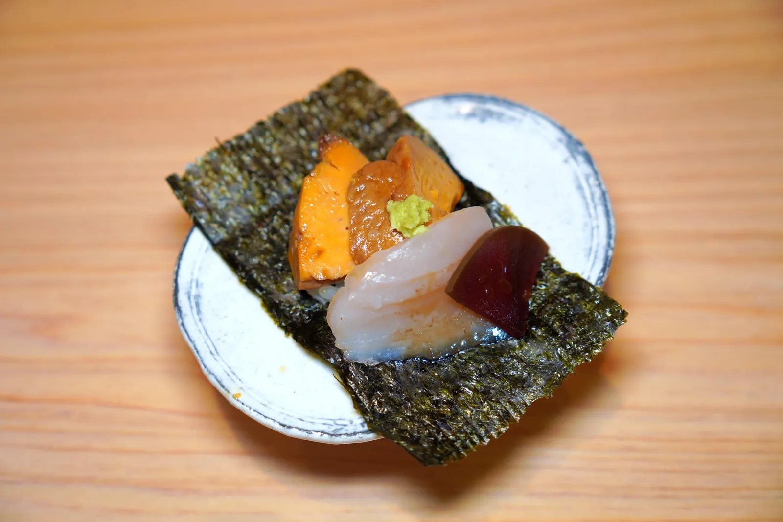 Ankimo/Tairagaiอังกิโมะหรือตับปลาอังโกะที่ผ่านการต้มกับมิริน สาเก และโชยุจนมีเนื้อสัมผัสที่นุ่มละมุนและครีมมี่ตัดกันกับความฉุนของวาซาบิ ข้างกันคือหอยกาบยักษ์หรือไทระไก ไฮไลท์ของจานนี้การใส่ Narazuke หรือแตงโมจิ๋วที่ผ่านกระบวนการดองตามแบบของจังหวัด Nara จนมีความนุ่มคล้ายเจลลี่มาด้วย ส่วนด้านล่างรองด้วยข้าวแล้วห่อด้วยสาหร่ายอีกทีหนึ่ง (15/20)